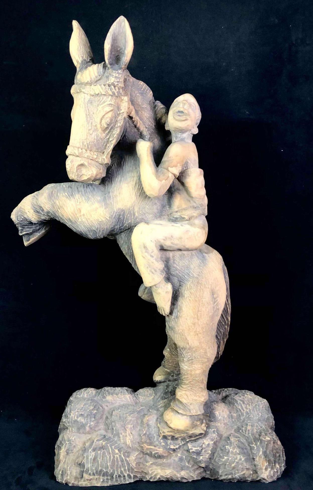 Hand Carved Wooden Sculpture of a Large Donkey: This lot contains a beautiful hand carved wooden sculpture of a donkey carrying a man on his back. The artwork is signed on the back left by R.Volcy. Volcy used palm wood to sculpt his