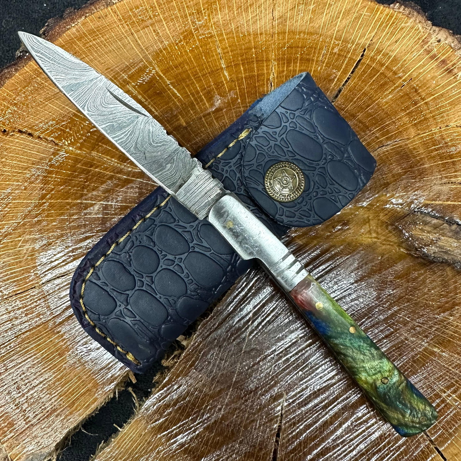 MHS Cutlery Steel Folded Blade Pocket Knife Multi Color Handle Design Q77: Folding blade pocket knife by MHS Cutlery featuring a layered patterned steel blade and decorative spine work. The handle has a contoured, multi-colored wood/resin-style grip with metal mosaic pin acc