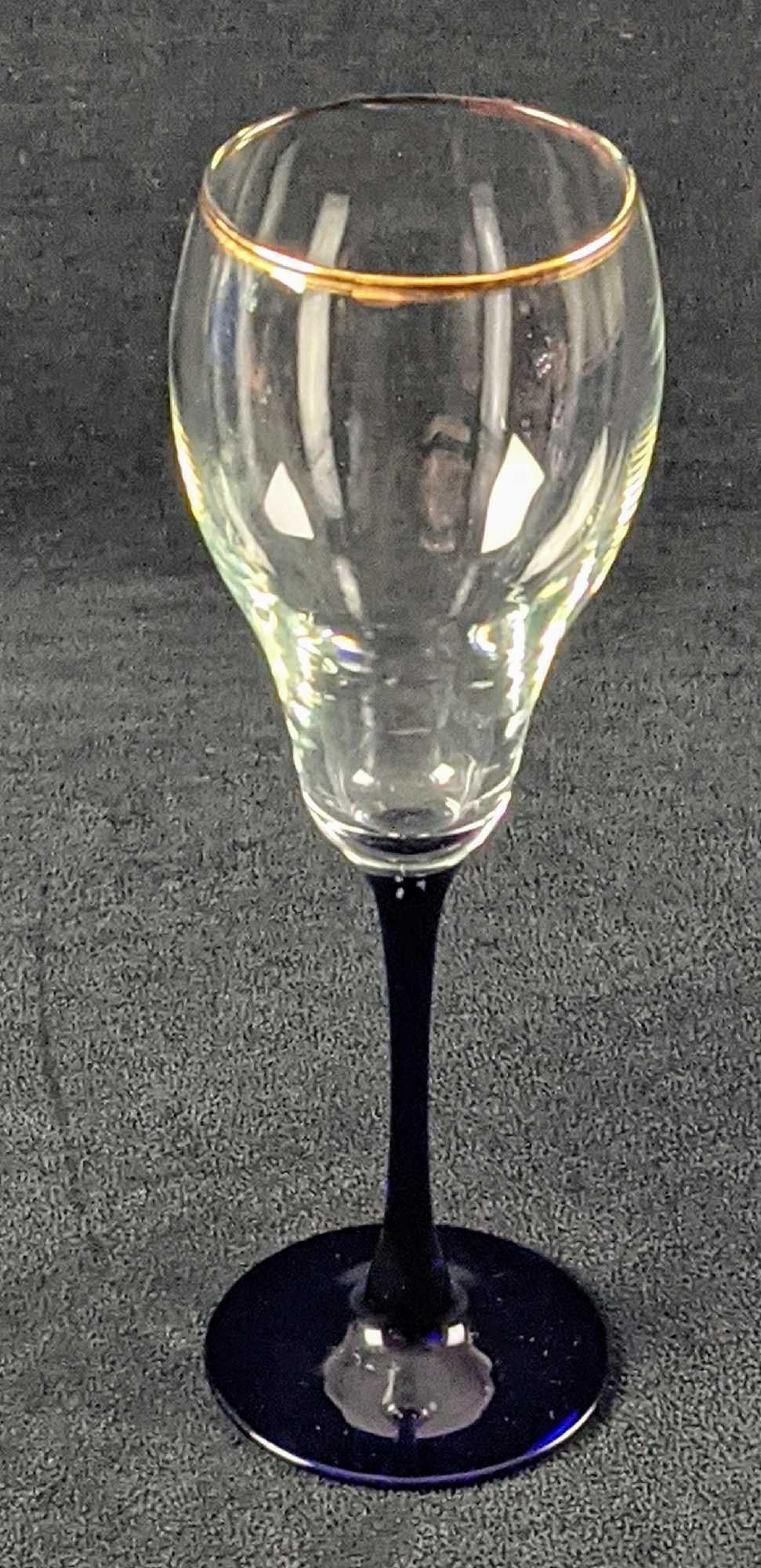 Clear Wine Glass With Cobalt Blue Stem And Base: Clear Wine Glass With Cobalt Blue Stem And Base, along with a gold-tone trim on the top. The maker and date of creation are unknown. Glass is approx 2 1/2" x 2 1/2" x 9 and is in a good, used conditio