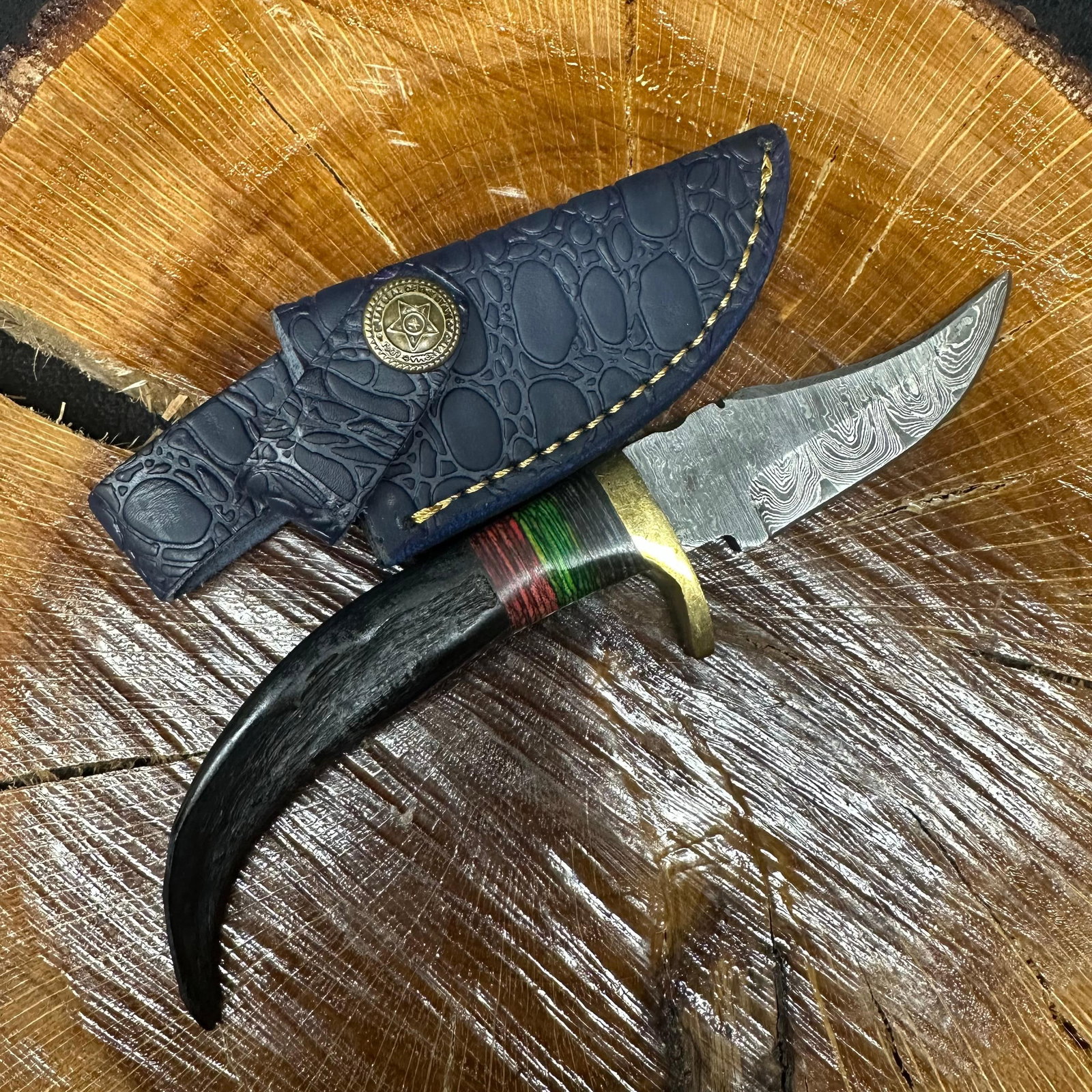 Short Fixed Blade Knife MHS Cutlery Horn Handle Blue Sheath R36: Fixed small blade knife by MHS Cutlery featuring a textured steel blade and decorative spine work. The handle has a contoured, horn-style grip with metal mosaic accents. Includes a fitted blue leather