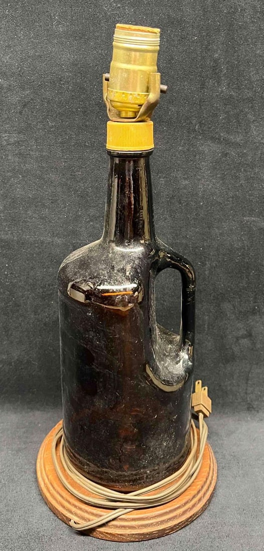 Large Glass Jug Lamp With A Wood Circle Base: This lot contains a Large Glass Jug Lamp With A Wood Circle Base. It is approx 7" x 7" x 15 1/2" and it weighs about 3.1lbs. Overall the Jug Lamp is in good used condition with some light wear from