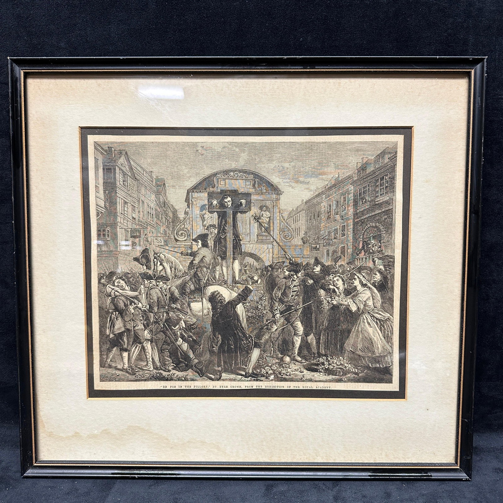 After Eyre Crowe De For In The Pillory Framed Engraving Print: Black and white engraving depicting a public punishment scene with a figure in the pillory surrounded by a crowd in a street setting. Plate titled “De For In The Pillory” after Eyre Crowe,