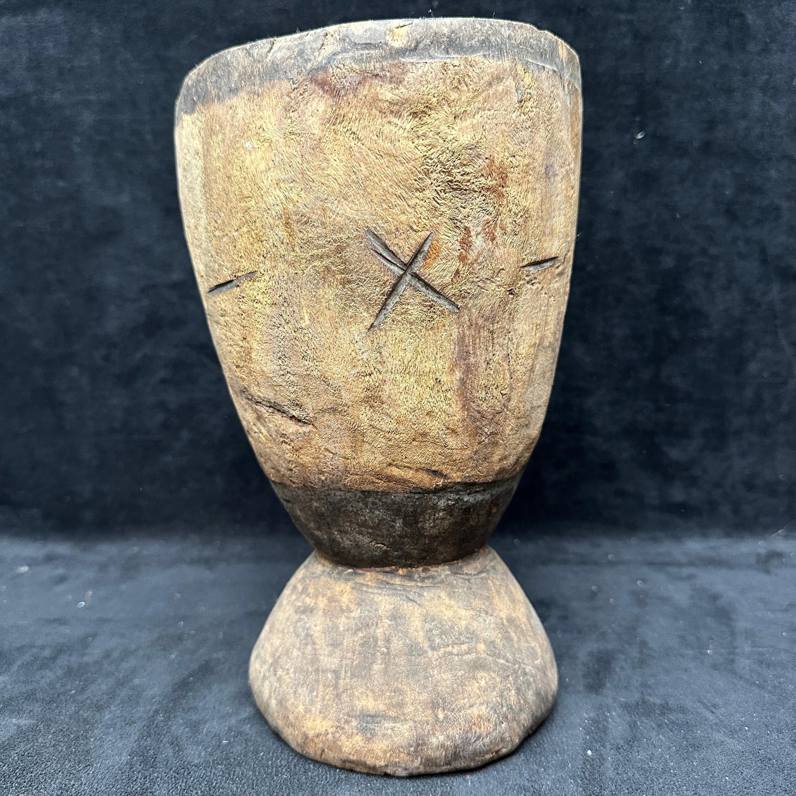 African Carved Wooden Mortar Vessel With Incised Markings: Hand-carved wooden vessel or mortar form featuring a flared rim and pedestal base. Exterior shows incised cross and linear markings. Surface exhibits heavy wear, age cracking, and patina consistent wi