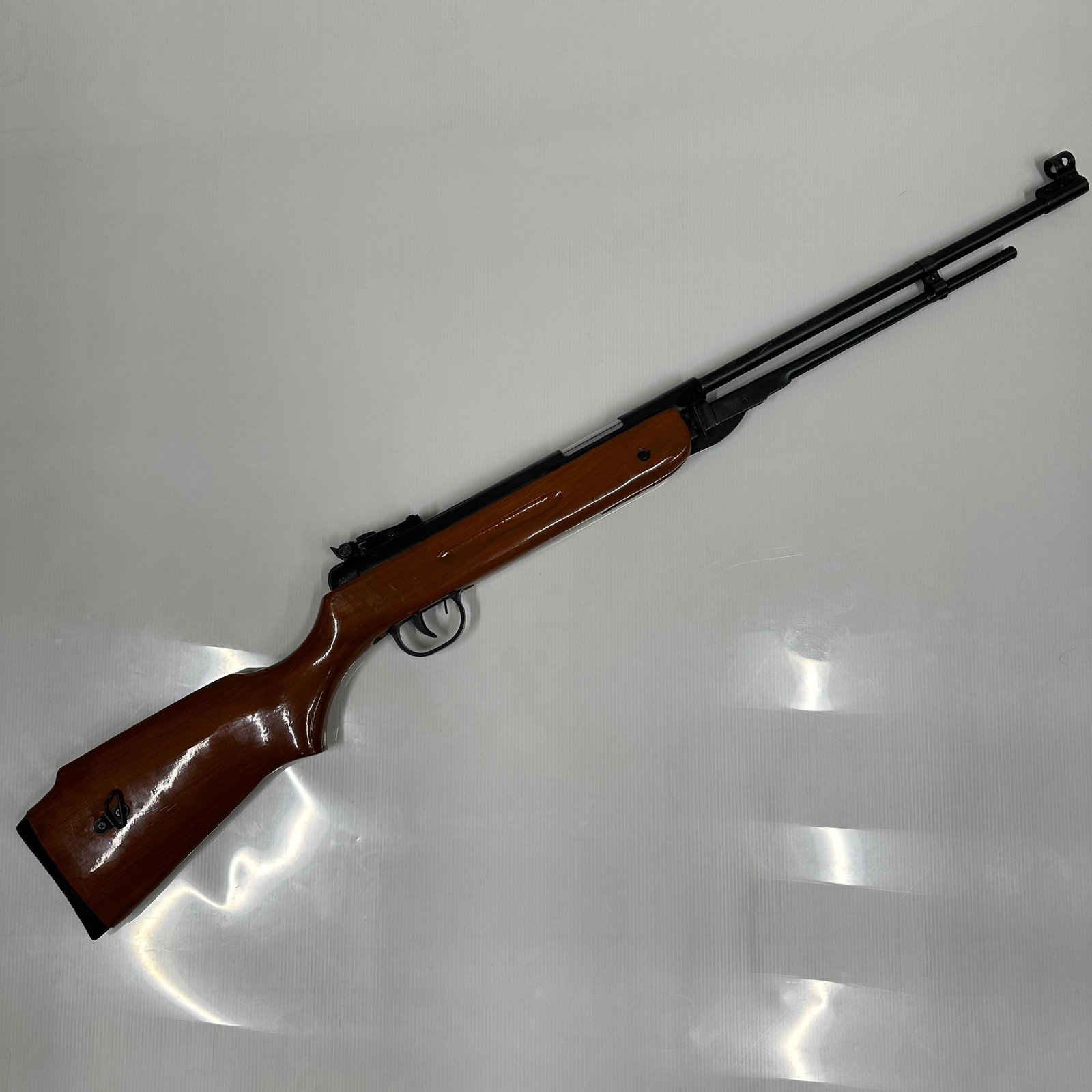 Vintage Break Barrel Air Pellet Rifle With Wood Stock Unmarked: Vintage break-barreled style air pellet rifle with hardwood stock and adjustable rear sight. Features a metal barrel and receiver with a rubber butt plate. Markings and caliber not observed, unmarked.