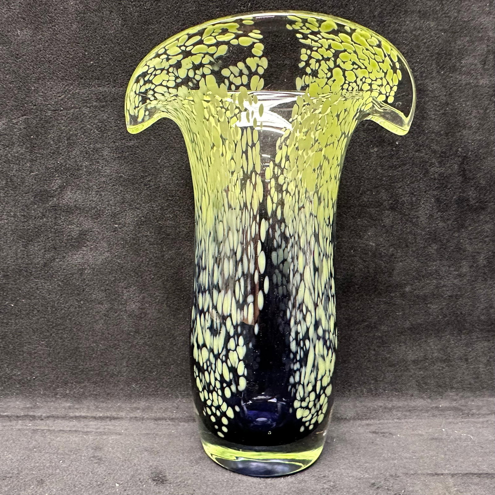 Green and Deep Cobalt Blue Art Glass Vase with Pulled Feather Rim Decoration: Hand-blown art glass vase featuring a flared, ruffled rim and cylindrical body. Decorated with pulled feather-style mottled inclusions in lime green over a deep cobalt blue ground. Clear-to-green rim 