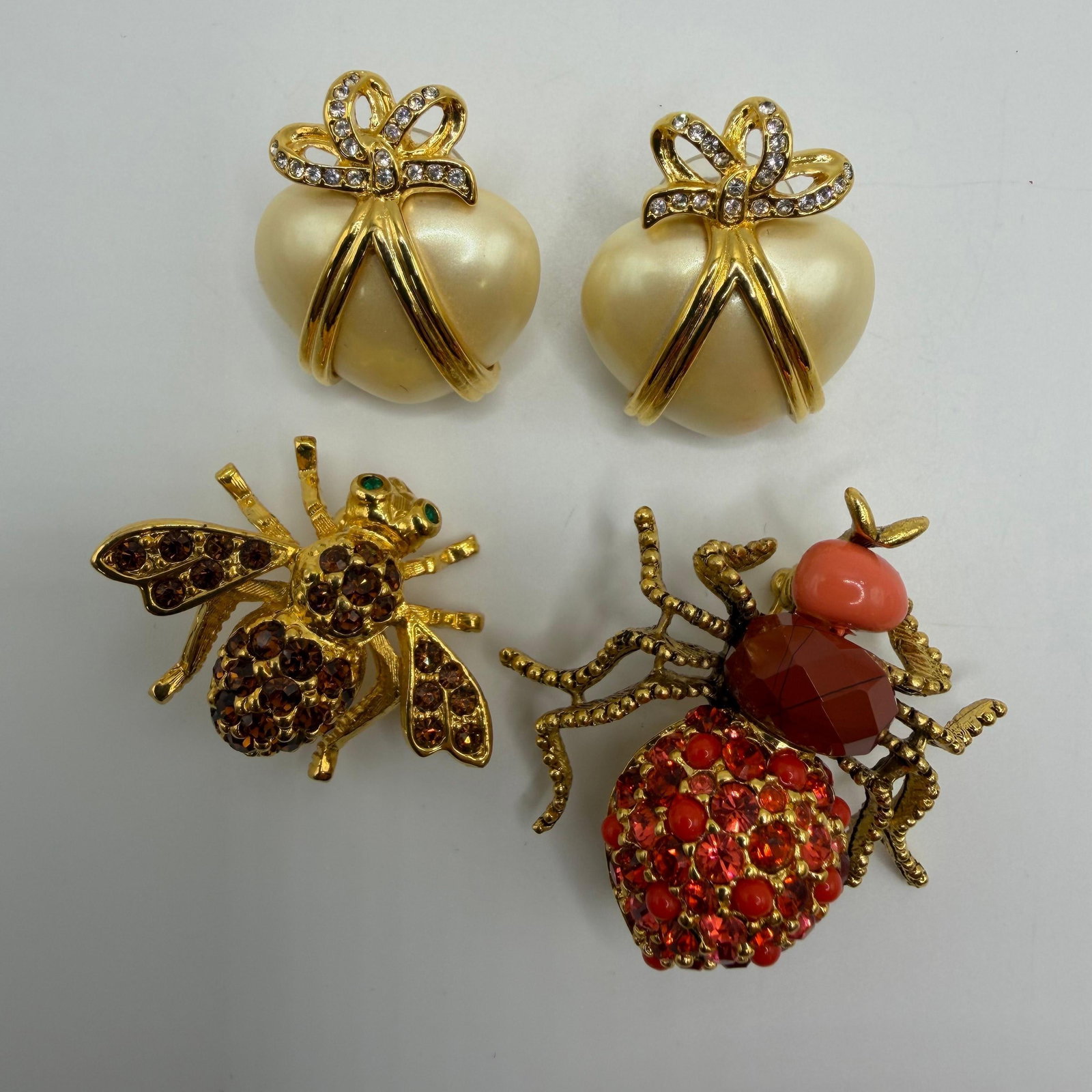 Joan Rivers Heart Bee and Ladybug Insect Jewelry Group HH32: A Joan Rivers jewelry assortment featuring a pair of cream-tone heart earrings with crystal bow accents, an amber crystal bee brooch, and a red crystal ladybug insect brooch with coral-tone accents. A