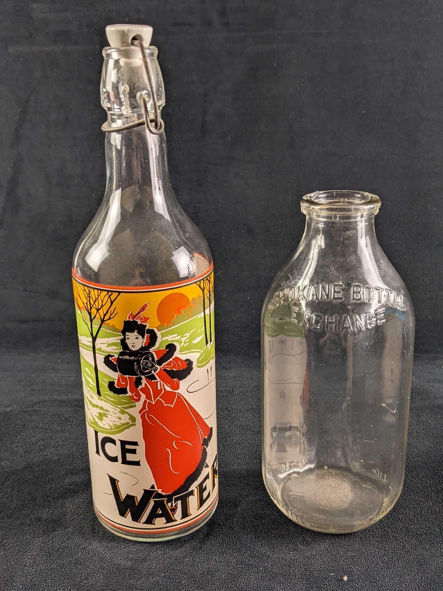 Vintage Ice Water Bottle And Glass Milk Bottle: This lot includes: (1) "Ice Water" Bottle With Original porcelain stopper. Has an image of a well-dressed woman as she skates. Is approx 4" x 4" x 12". Has some light surface 