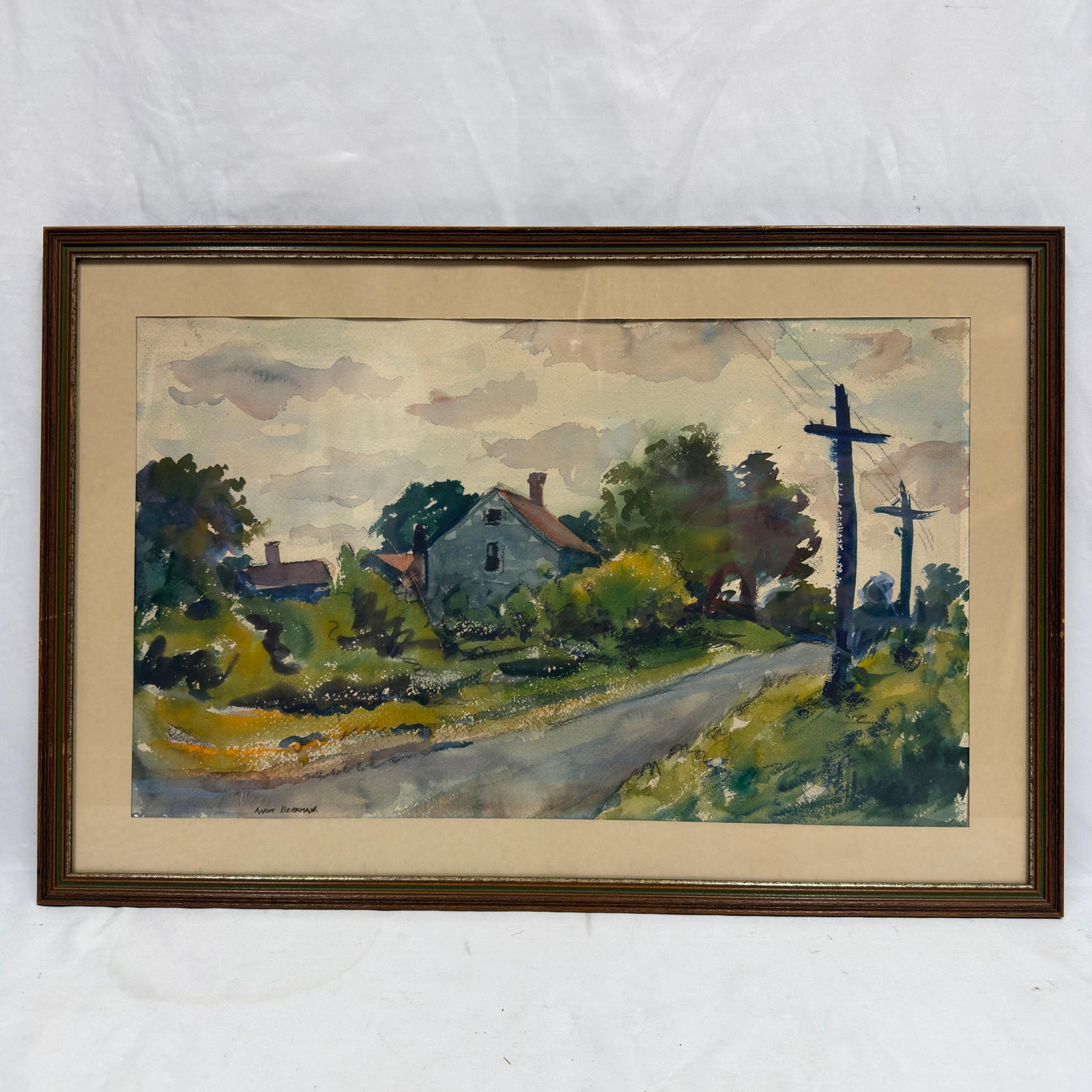 Aaron Berkman Framed Original Modernist Watercolor Landscape: Original watercolor on paper depicting a quiet rural roadside landscape with a farmhouse, trees, telephone poles, and a dramatic cloud-filled sky. Signed "Aaron Berkman" lower left. Presented 