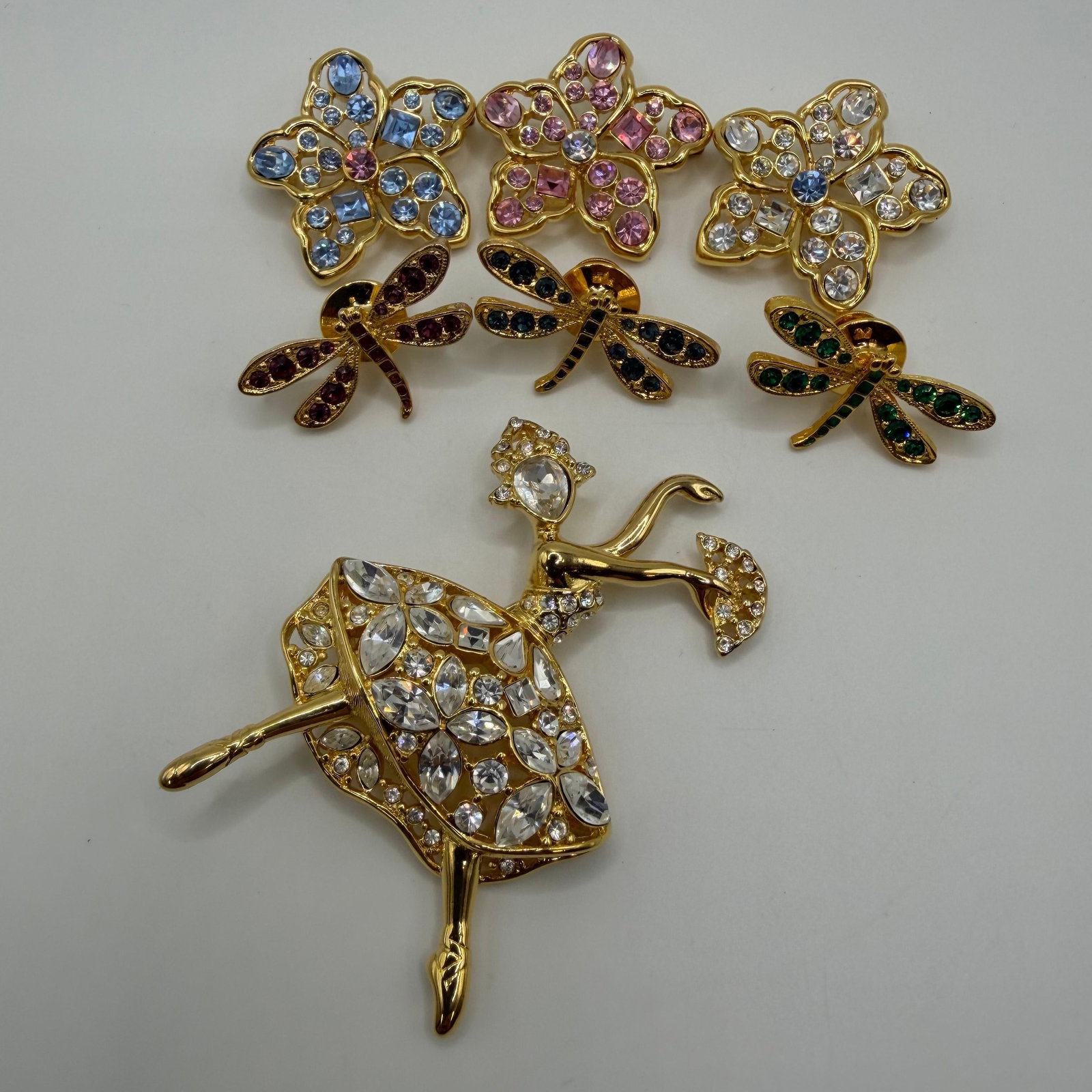 Nolan Miller Figural Fashion Designer Brooches Dragonflies HG62: Collection of seven Nolan Miller figural brooches, each marked on the reverse. Includes a large rhinestone ballerina dancer, three floral brooches accented with blue, pink, and clear rhinestones, and 
