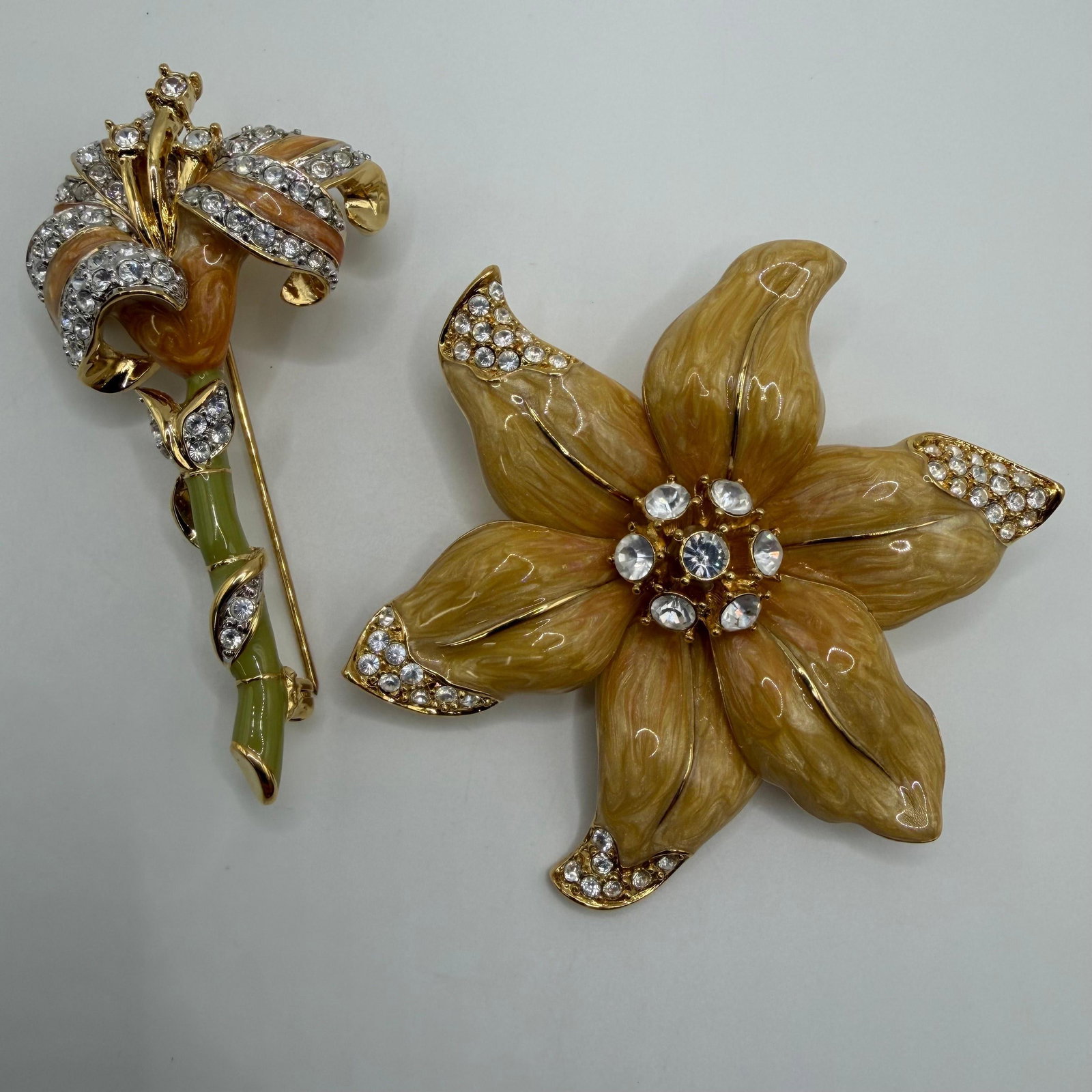 Nolan Miller Floral Rhinestone Enamel Designer Brooch Pair AB20: Pair of signed Nolan Miller designer costume brooches. Includes a long-stem lily featuring marbled peach enamel petals, green enamel stem, and clear rhinestone accents, along with a matching marbled p