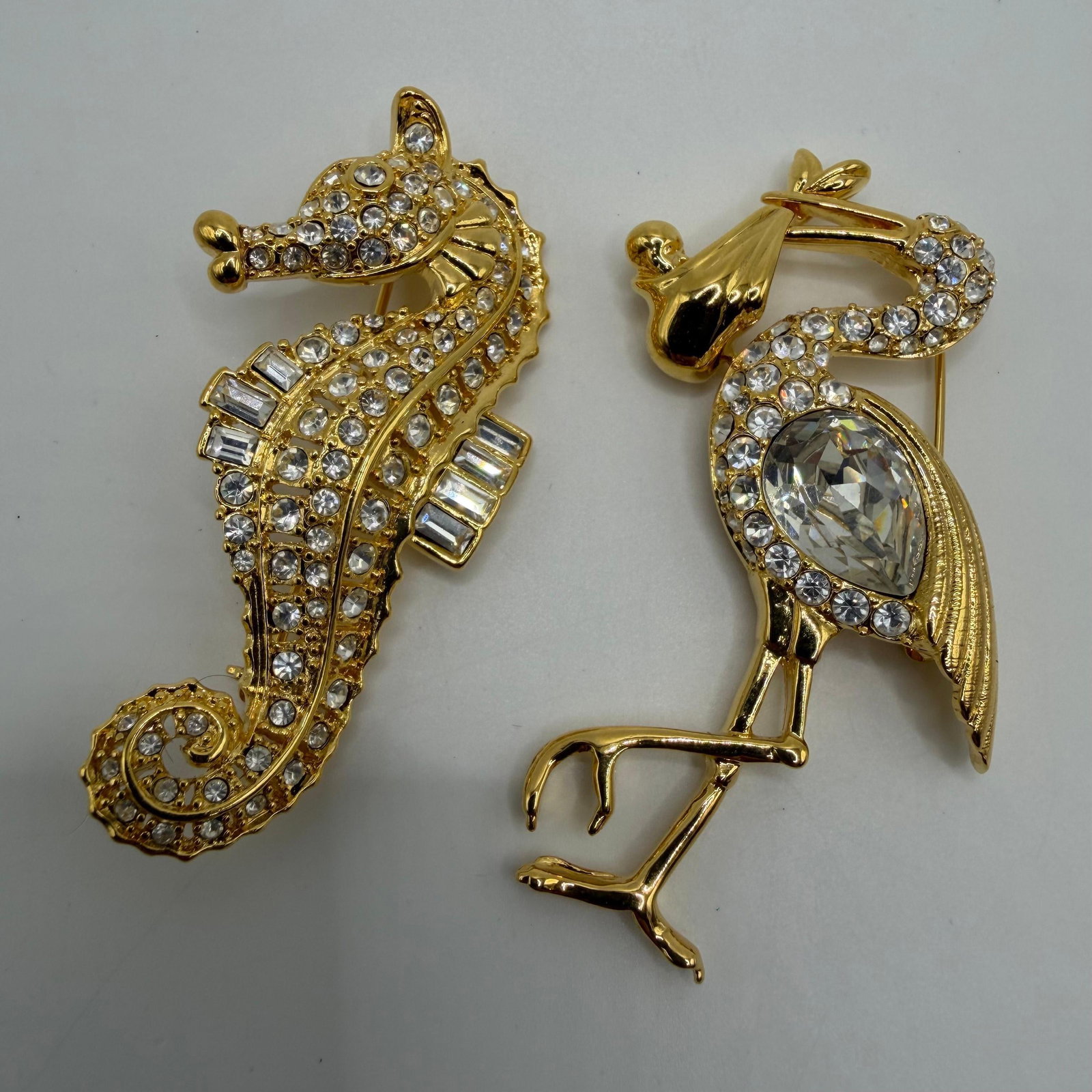 Seahorse and Flamingo Pair of Nolan Miller Clear Rhinestone Animal Brooches: Pair of signed Nolan Miller designer costume brooches, including a clear rhinestone seahorse with baguette crystal accents and a flamingo featuring clear rhinestones with a large faceted clear crystal