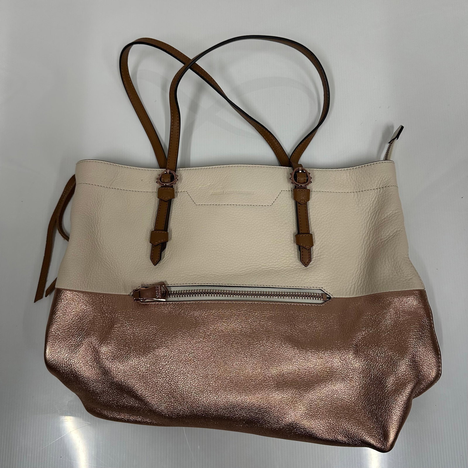 Aimee Kestenberg Leather Tote Bag Cream and Rose Gold: Aimee Kestenberg tote bag in cream pebbled leather with metallic rose gold lower panel. Brown leather shoulder straps with buckle detail. Top zip closure. Exterior front zipper pocket. Interior featur