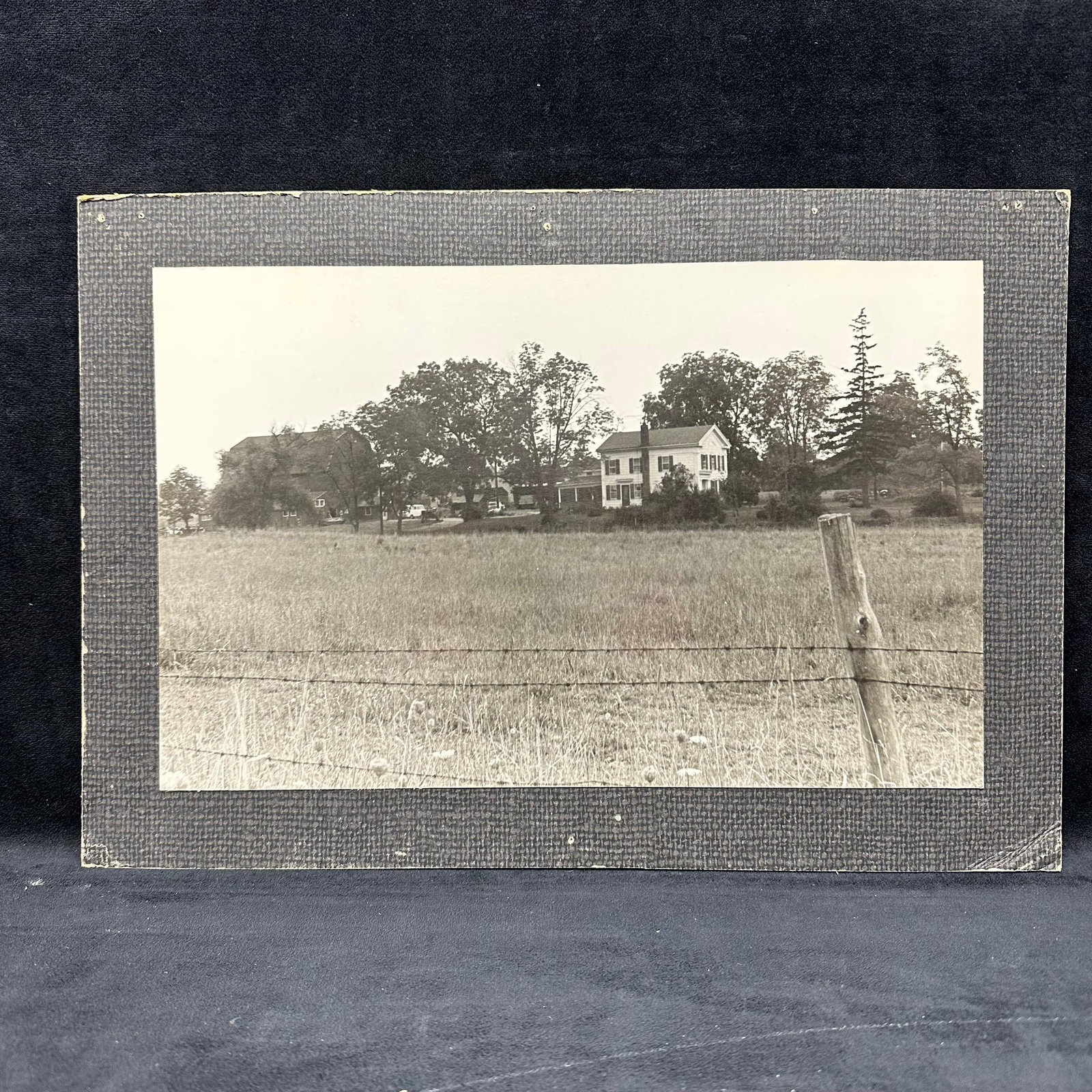 Vintage Silver Gelatin Photograph of Rural Farmstead Landscape: Vintage black and white silver gelatin photograph depicting a rural farmstead scene with a farmhouse, barn, trees, and open pastureland in the foreground. The composition shows a field with a barbed