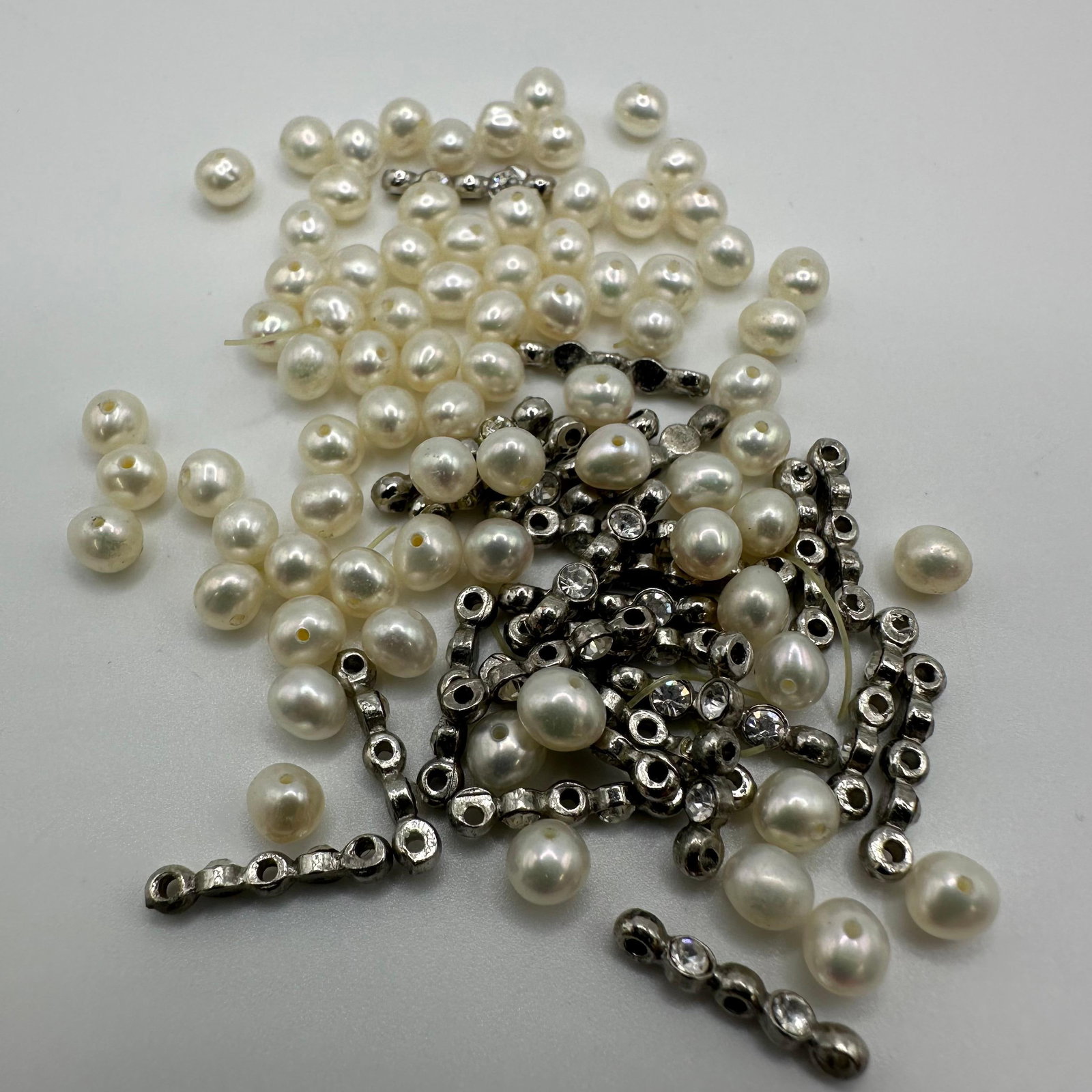 Natural Pearls and Costume Jewelry CZ Bead Accessories: An assorted lot of loose cream-tone natural pearl beads and silver-tone rhinestone/cubic zirconia spacer connectors. Pearls are pre-drilled for stringing. Spacers feature clear faceted rhinestones/CZ 
