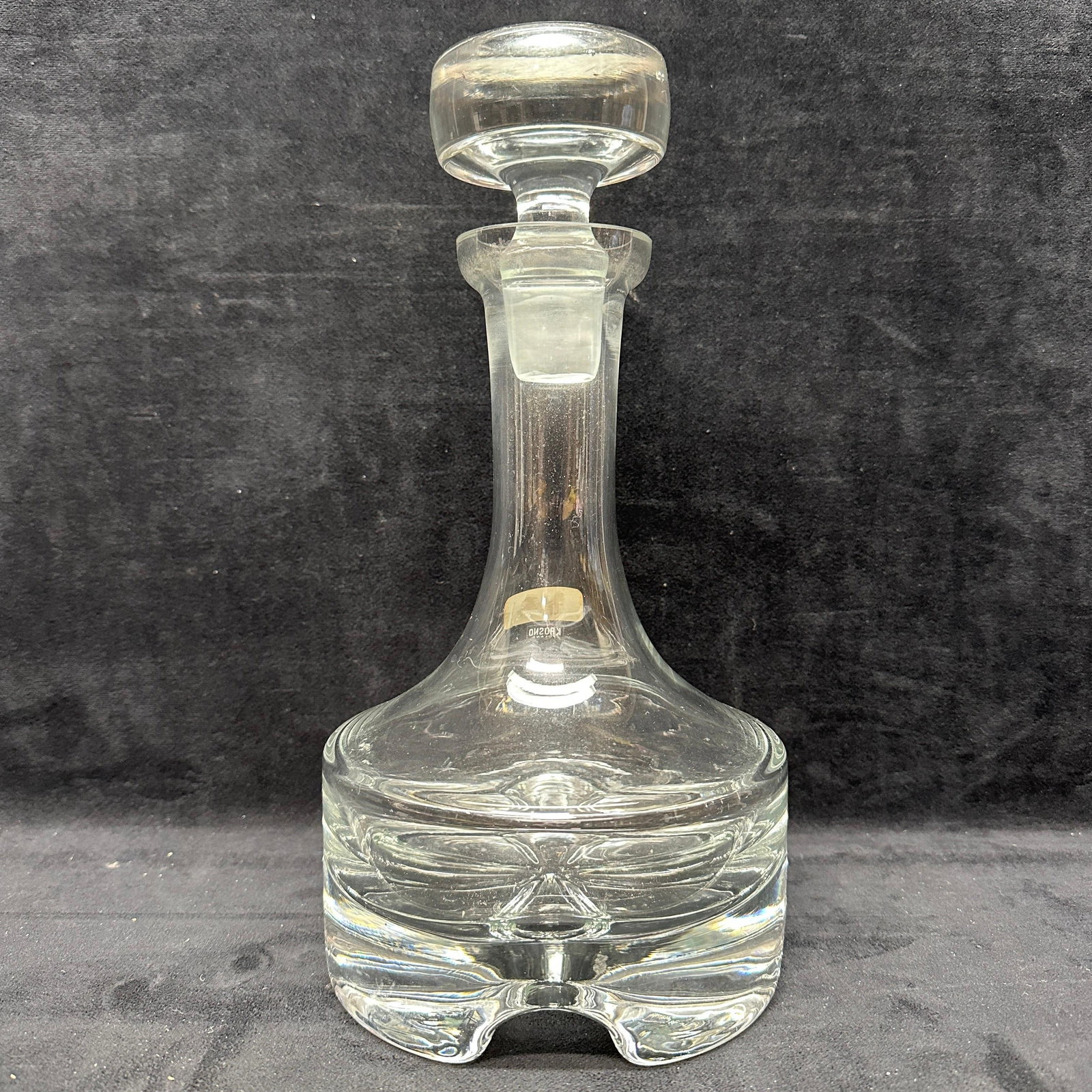 Krosno Poland Clear Art Glass Decanter With Stopper: Clear art glass decanter by Krosno, Poland, with original stopper. Features a flared neck and a heavy molded base with a stylized design. Retains original Krosno label. Shows light surface wear and