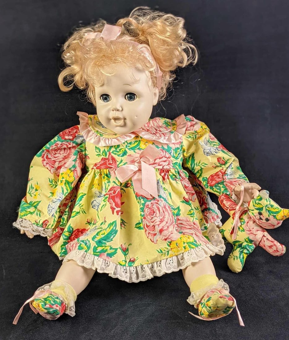 Happy Holly Collectible Second Generation Baby Girl Doll: Has a vinyl "porcelain-like" finish face, arms, and legs with a very soft huggable material-filled body. Styleable hair and ribbon with a matching dress, socks, and holding a matching toy bear. 