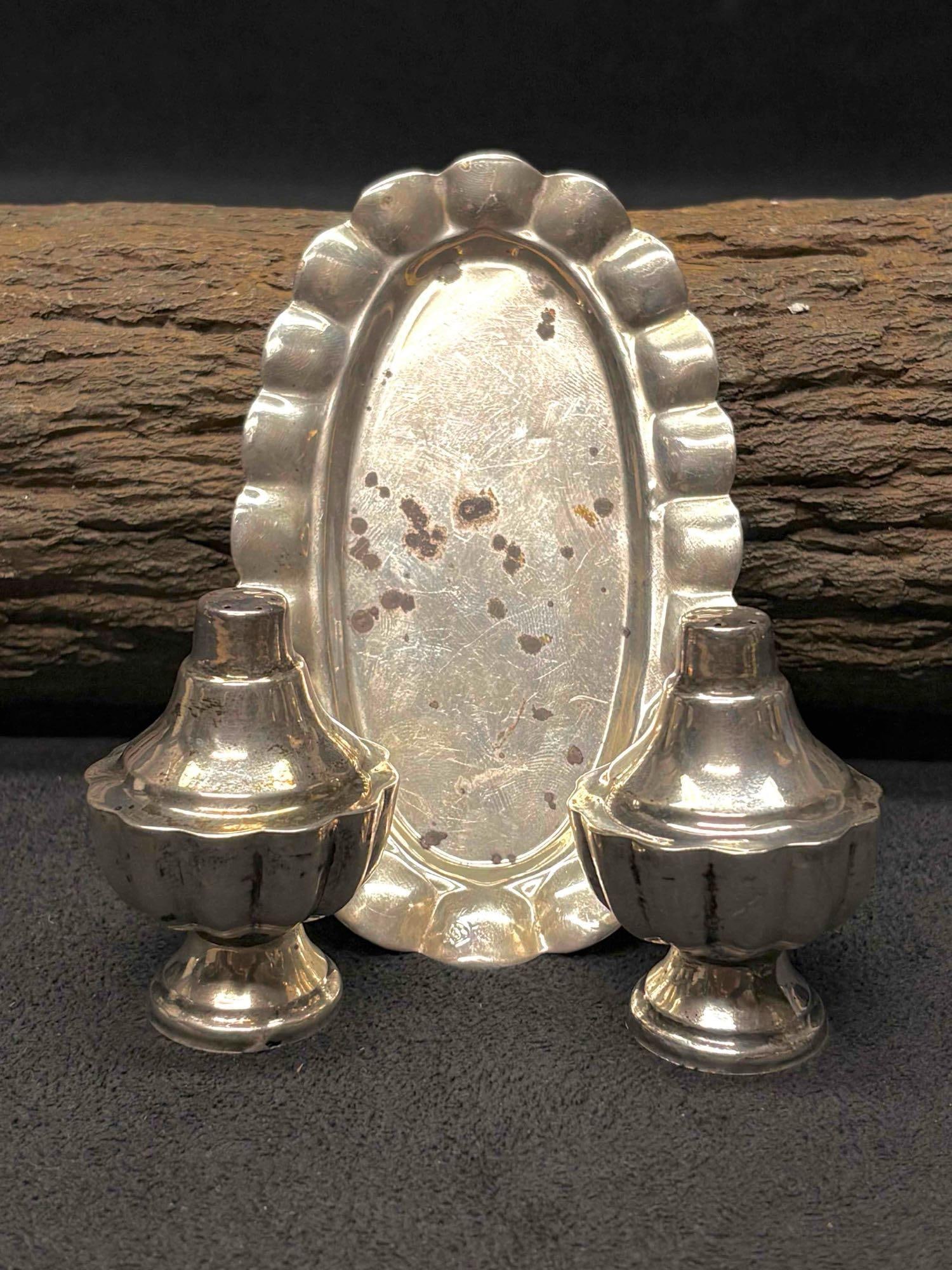 3pc 1970s Mexican 925 Sterling Silver Salt Shakers and Trays: This lot containers a salt and pepper shaker, displaying ornate Mexican motifs and ribbed bodies. The base of the shakers unscrew, allowing it to be refilled. Due to age, the grooves and nooks of the