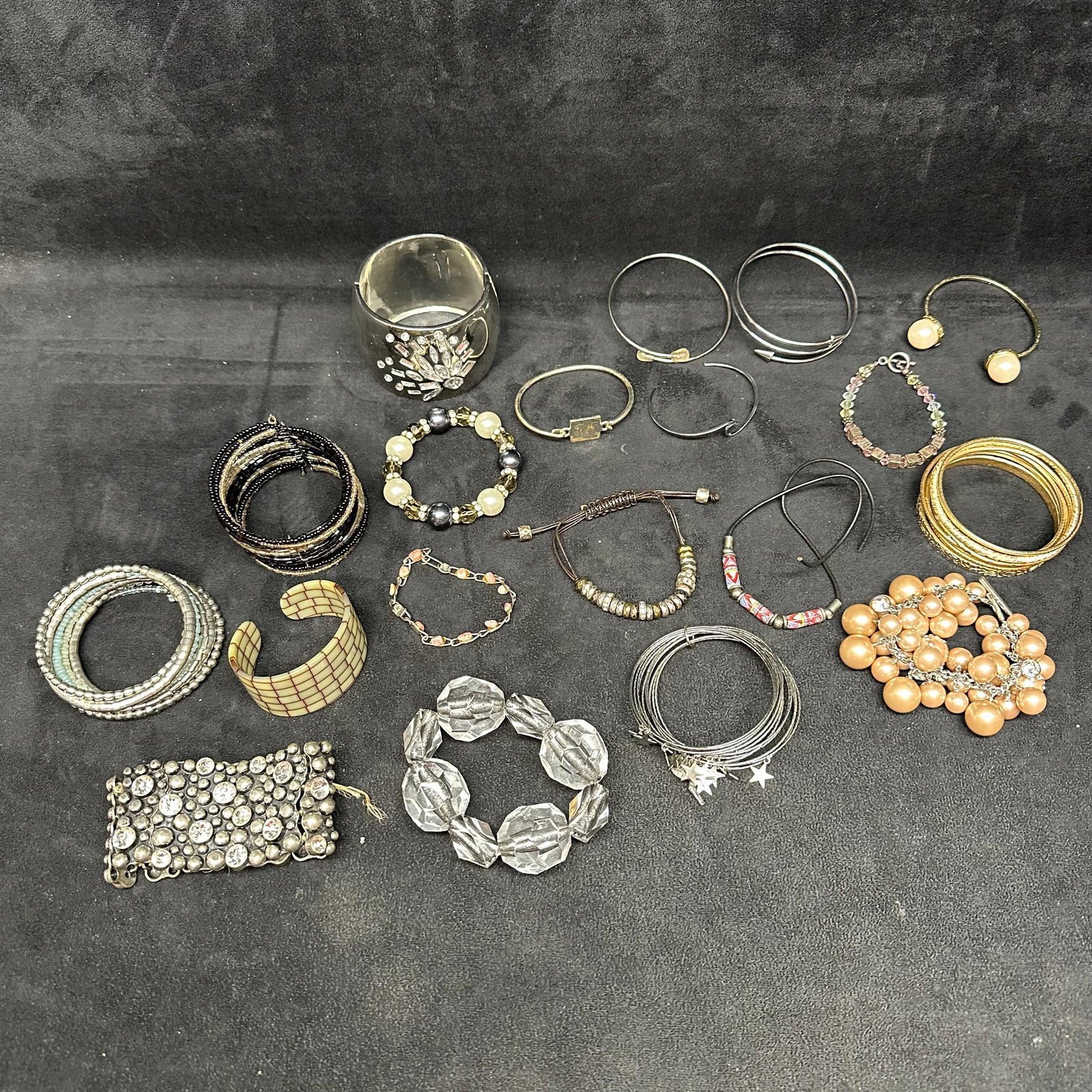 Large Assorted Costume Jewelry Lot Including Bracelets Bangles and Cuffs: Mixed lot of assorted costume jewelry, primarily consisting of bracelets and bangles. Includes a wide silver-tone cuff bracelet with clear rhinestone accents, multiple stacked bangles in gold-tone and