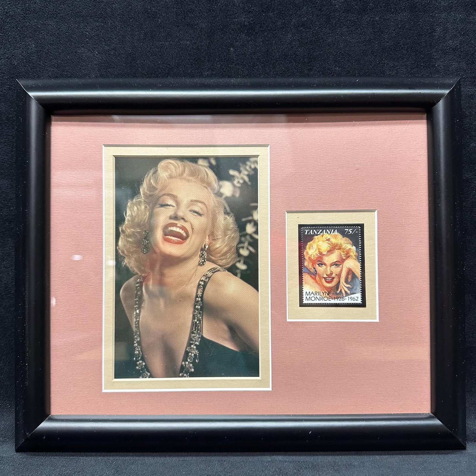 Framed Marilyn Monroe Photograph with Tanzania Commemorative Stamp Display: Framed display featuring a color photographic image of Marilyn Monroe, paired with a Tanzania commemorative postage stamp honoring Marilyn Monroe, 1926–1962. The stamp is mounted to the right of