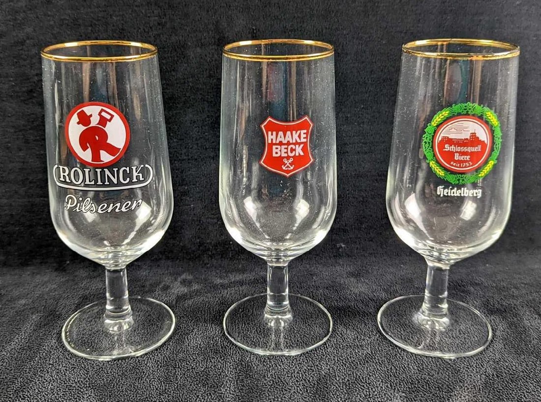 3 Vintage Gold-Rim Stemmed German Beer Glasses: This lot includes: (1) Rolinck Pilsener. (1) Schlossquell Biere. (1) Haake Beck. Each glass is approx 2 1/2" x 2 1/2" x 6 1/2" and together they w
