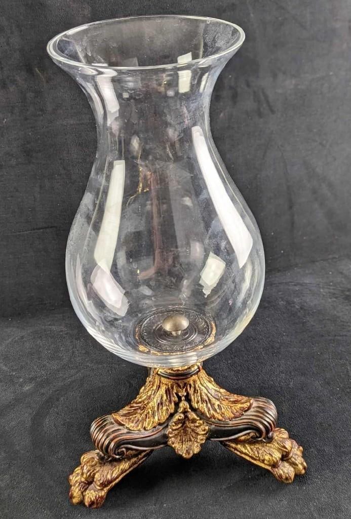 Table Footed Glass Vase: Table Footed Glass Vase. The maker and date of creation are unknown. The vase is glass, while the feet are resin. The glass vase can be easily unscrewed from the base for cleaning. The vase was made