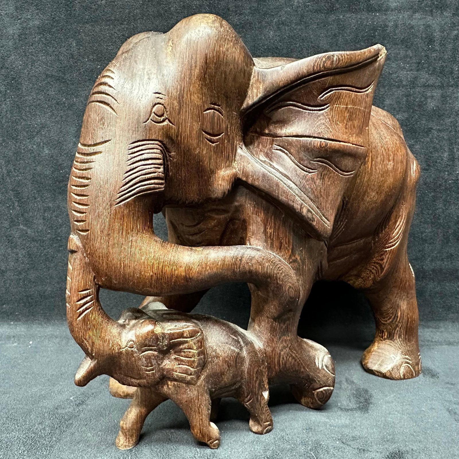Solid Hand Crafted Wooden Elephant Mother and Child Animal Sculpture: Hand-carved wooden sculpture depicting an adult elephant with a calf. Solid wood construction with dark-stained finish, featuring carved details throughout, including textured ears, trunk, and body co