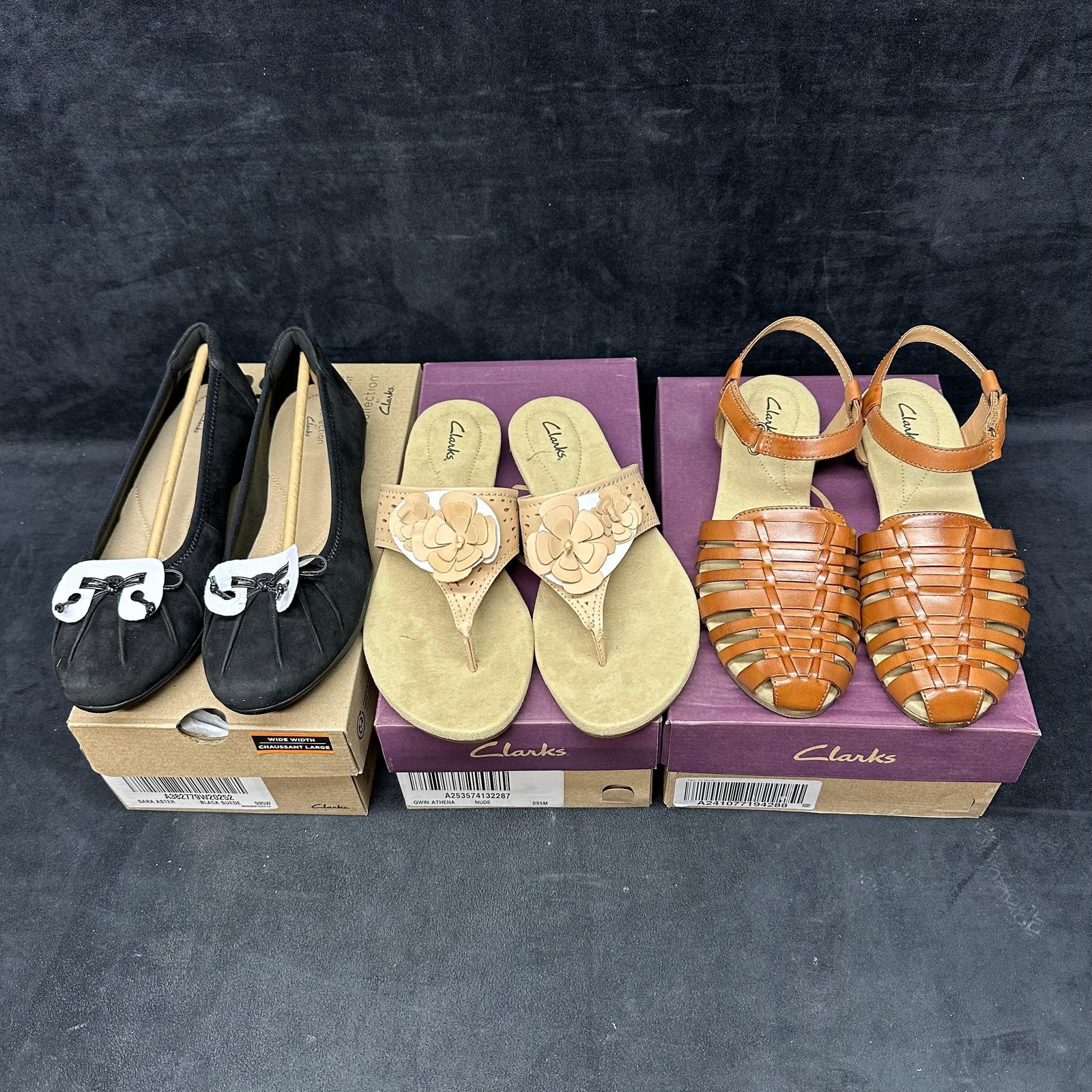 Clarks Womens Sandals and Shoes Lot of Three Pairs: Set of three pairs of Clarks women’s shoes, each appearing new in boxes. Includes one pair of black flats with white and black bow detail, one pair of nude thong sandals with floral applique