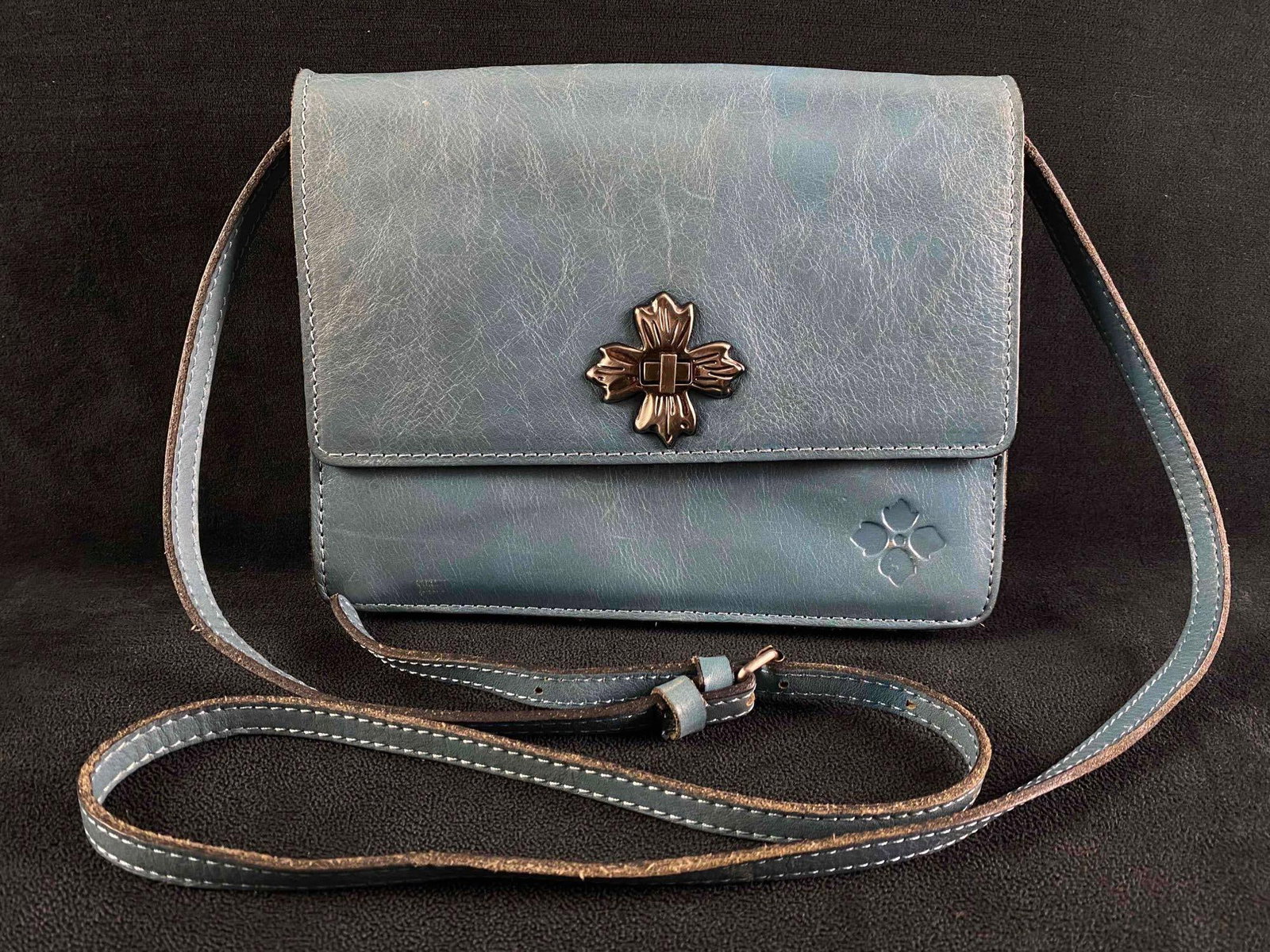 Patricia Nash Consilina Blue Leather Crossbody: Patricia Nash Consilina Blue Leather Crossbody Blue leather Consilina crossbody purse. The front features a clasp that turns to fasten the top flap shut, as well as an embossed logo. The inside h