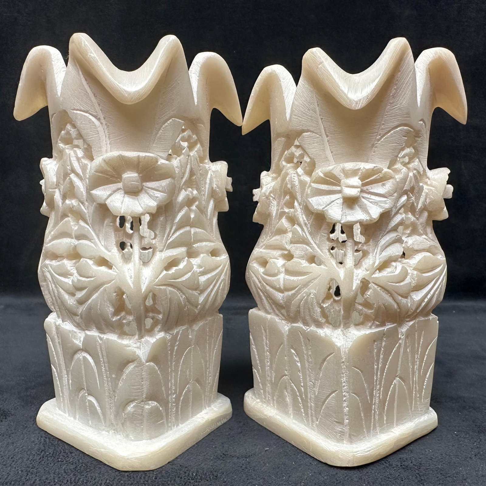 Pair of Hand Carved Floral White Alabaster Soapstone Style Scalloped Rim Vases: Pair of hand-carved stone vases, featuring intricate floral and leaf motifs throughout. Each vase has a softly scalloped rim and relief flower carvings around the body. The creamy, semi-translucent st