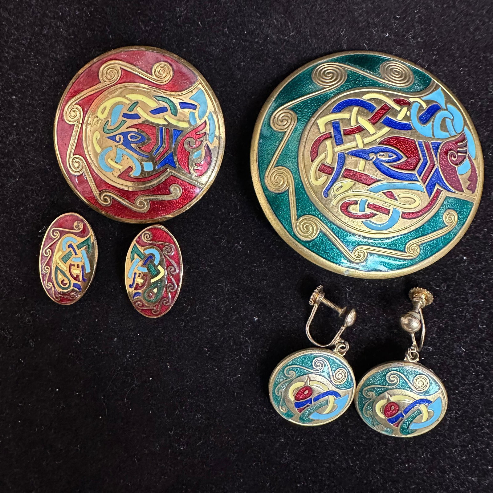 Vintage Celtic Enamel Jewelry Group Brooches and Earrings Made in Ireland: Group of vintage Celtic-style enamel jewelry featuring traditional knotwork designs in red, green, blue, and gold tones.Includes two round enamel brooches (one larger, one smaller), one pair of oval e