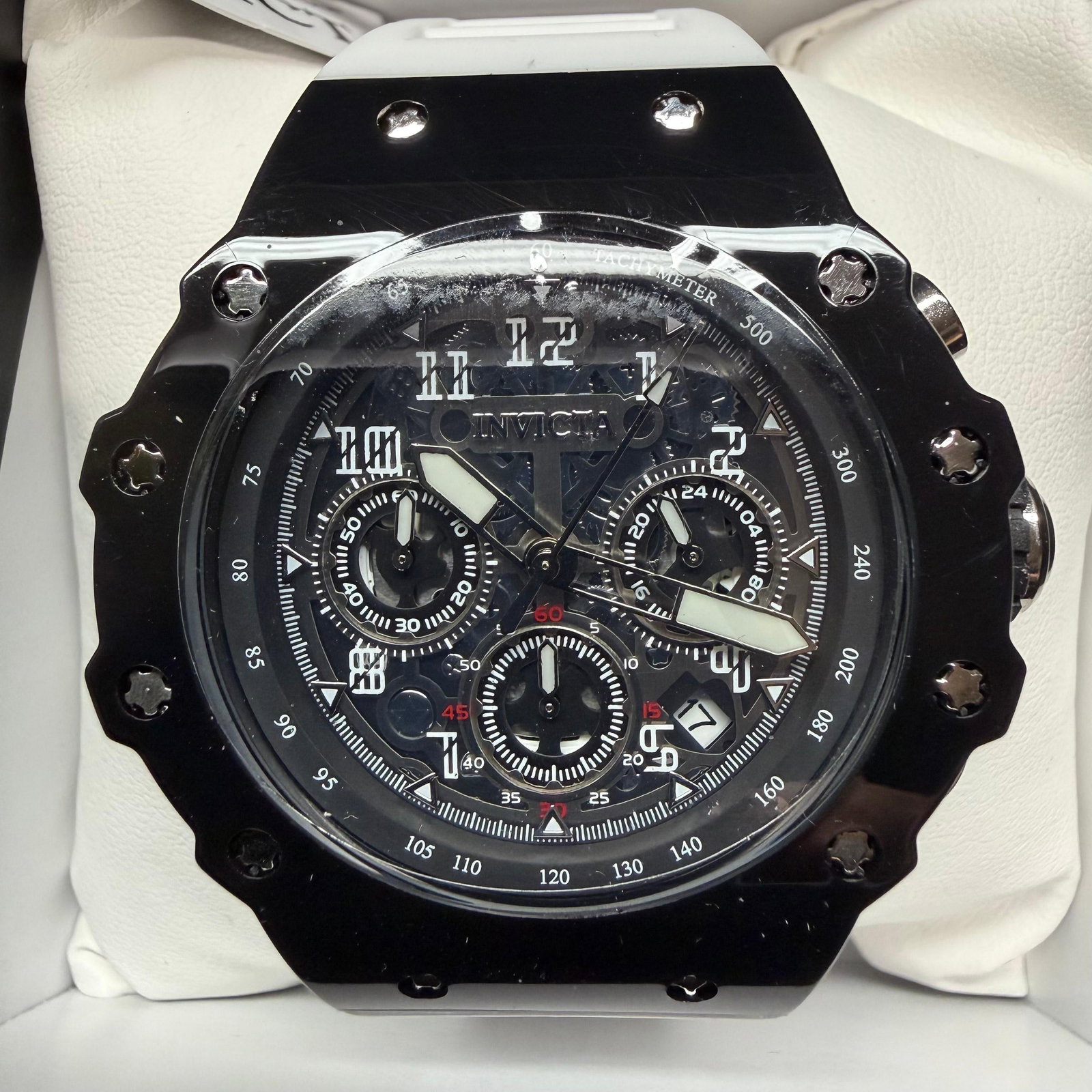 Invicta Men Black Chronograph Watch White Silicone Strap: Invicta men’s chronograph wristwatch featuring a black case and bezel, skeletonized multi-function dial, tachymeter scale, luminous-style hands and markers, date window, and white silicone/