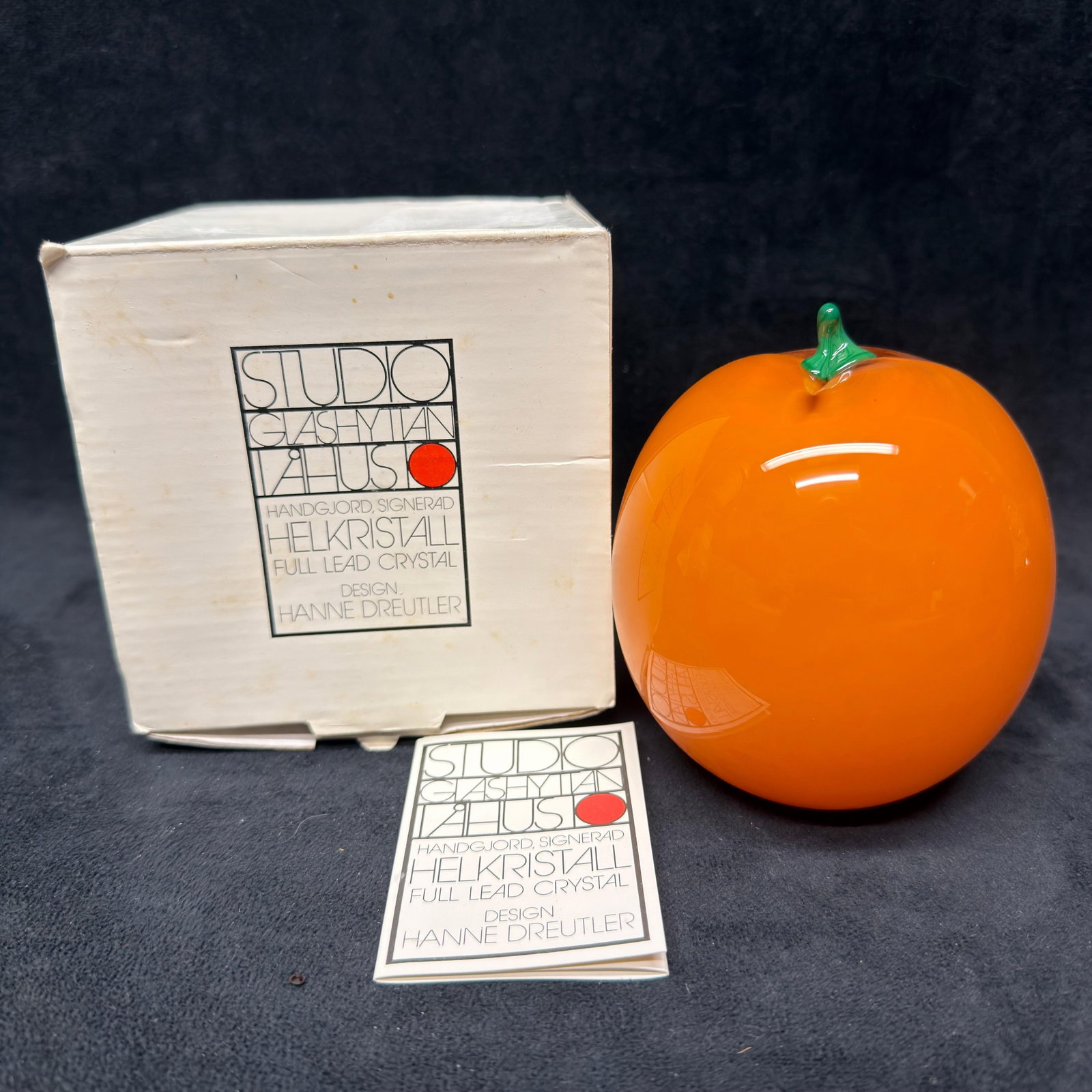 Hanne Dreutler Studio Ahus Swedish Art Glass Orange Apple: Handcrafted Swedish full lead crystal art glass apple by Hanne Dreutler for Studio Glashyttan Ahus. Rich opaque orange body with applied green glass stem and leaf. Signed/engraved to underside