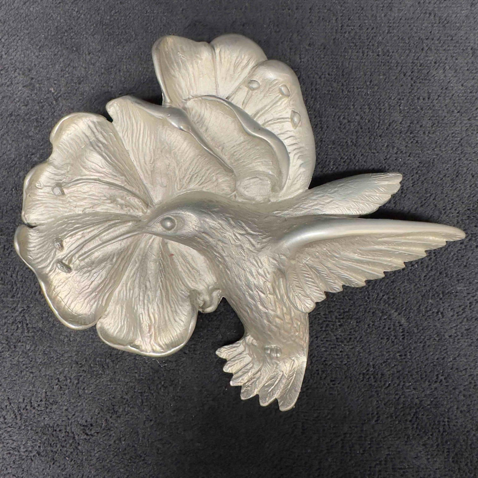 Humming Bird Metal Silver Toned Brooch Lapel Pin: Humming Bird Metal Silver Toned Brooch Lapel Pin. DR 94 etched marking on the back of the brooch lapel pin. The brooch features a butterfly clutch clasp closure. This item is in good pre-owned, previo