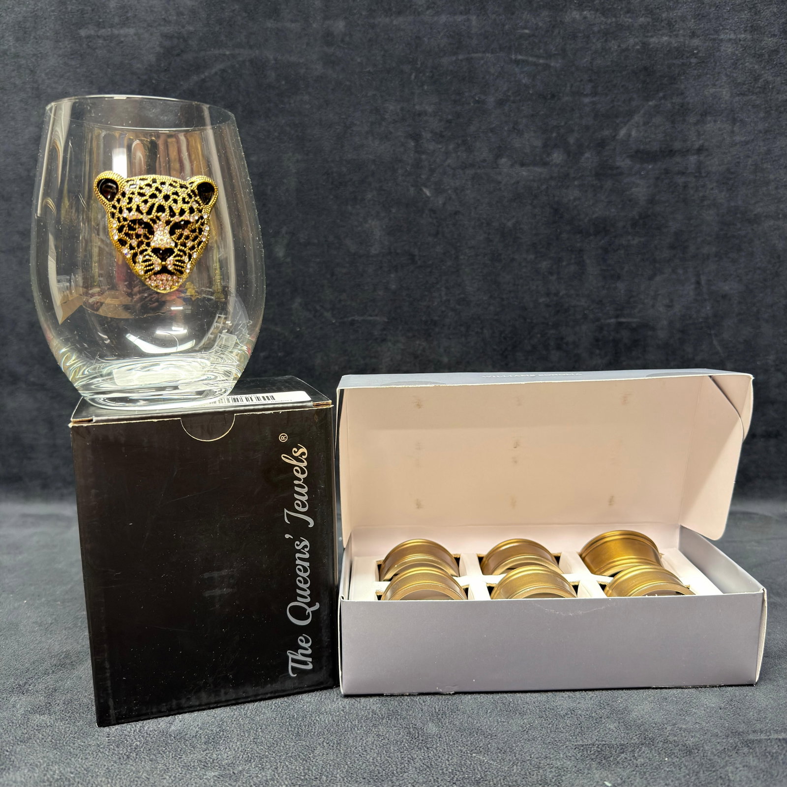 Williams Sonoma Brass Finish Pantry Napkin Rings and Queens Jewels Leopard Stemless Wine Glass: Decorative tabletop entertaining lot including a Williams Sonoma Pantry set of six brass-finish napkin rings in the original box and a The Queen's Jewels stemless wine glass featuring a jeweled le