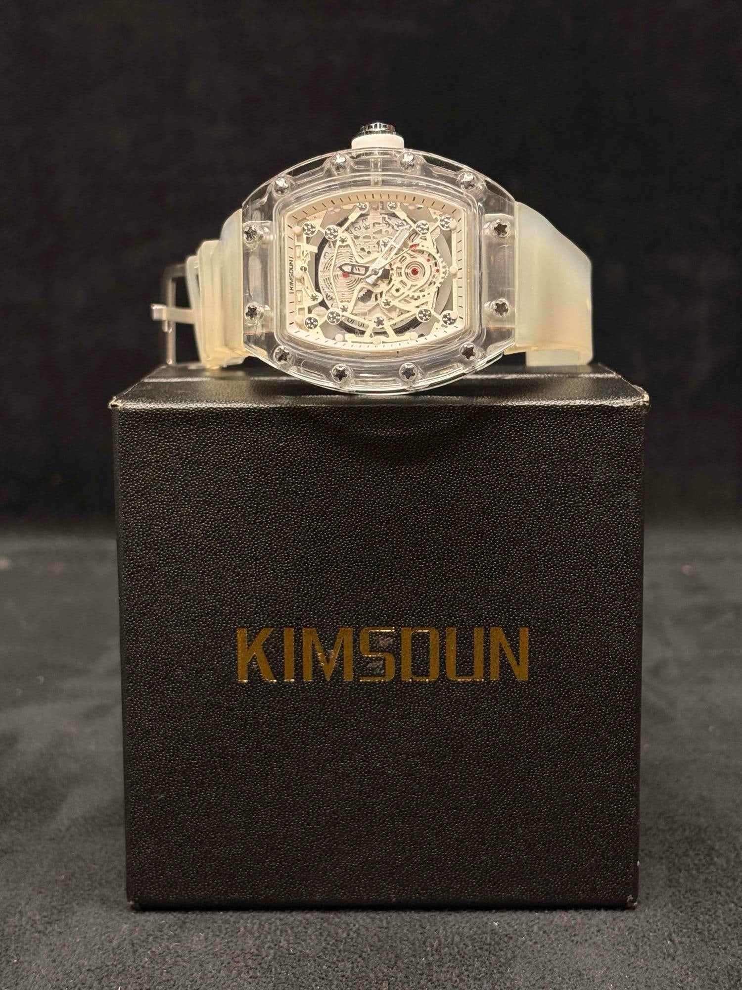 Kimsdun Tonneau Skeleton Dial Transparent Watch: This lot contains a skeletonized dial watch displaying visible mechanical movements within its transparent tonneau-shaped case. The straps are made of a frosty, semi-transparent silicone. The watch it