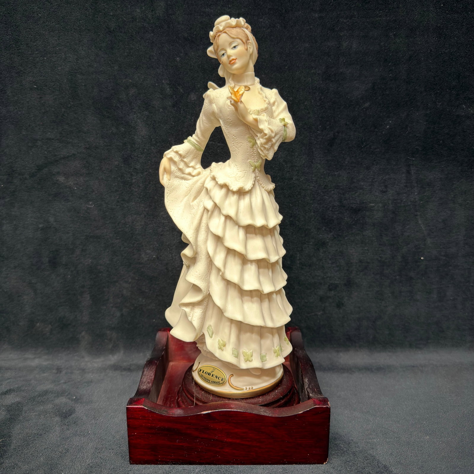 Giuseppe Armani Florence 0297F Little Butterfly Figurine with Wood Display Base R240: Giuseppe Armani Florence figurine titled Little Butterfly, model 0297F, made in Italy. Depicts an elegantly dressed Victorian lady admiring a butterfly with finely sculpted lace details and