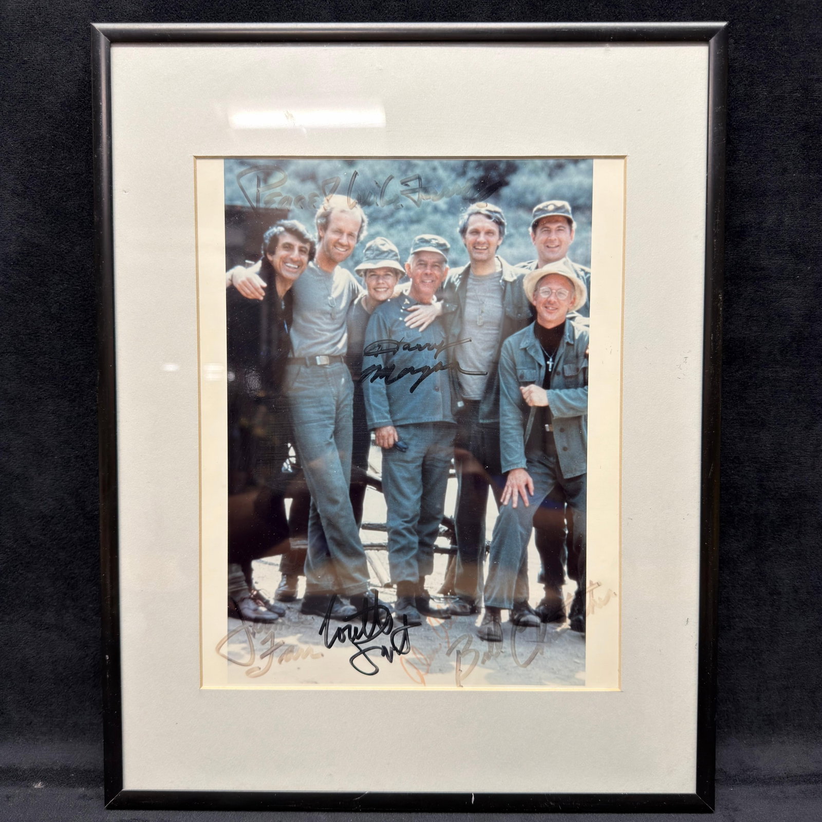 MASH Cast Framed Photo Signed Display R240: Framed color cast photograph from the television series MASH, appears to be signed by multiple cast members directly on the photograph. Visible signatures appear to include Alan Alda, Loretta