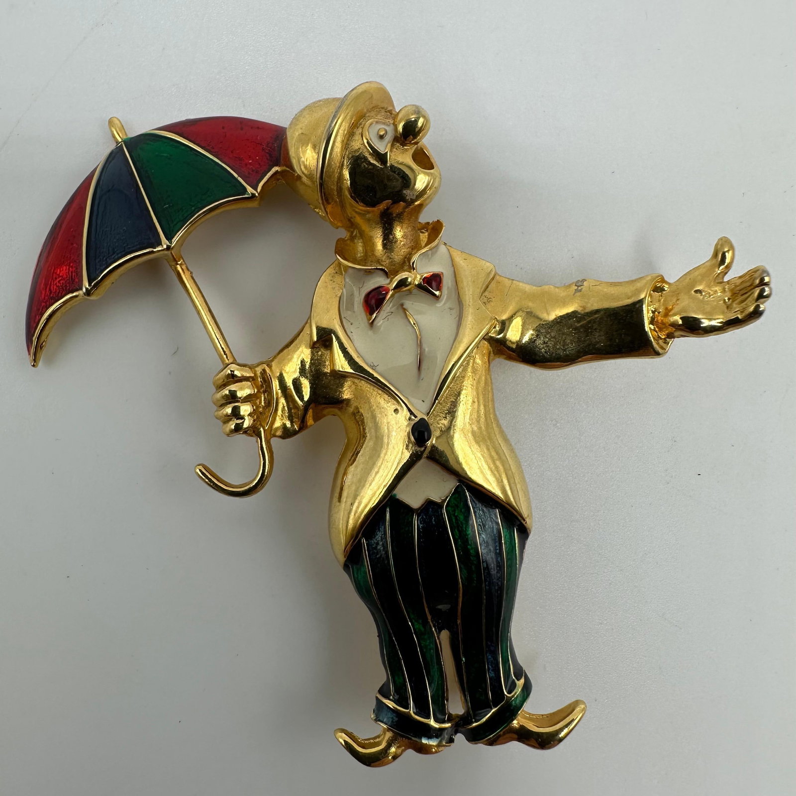 Vintage Clown with Umbrella Enamel Costume Gold Tone Brooch Pin: A metallic enamel gold-tone vintage brooch featuring a Clown holding an umbrella. No hallmarks noticed. This item is in pre-owned, previously displayed condition with wear and surface scratches. Pleas