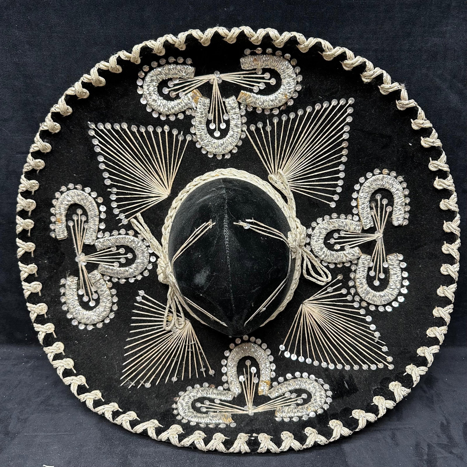 Black Velvet Mariachi Sombrero Hat with Silver Embroidery Pigalle Brand: Vintage Mexican-style mariachi sombrero featuring black velvet fabric with decorative silver-tone embroidery and cordwork throughout. The brim is accented with braided trim, and the crown is wrapped w