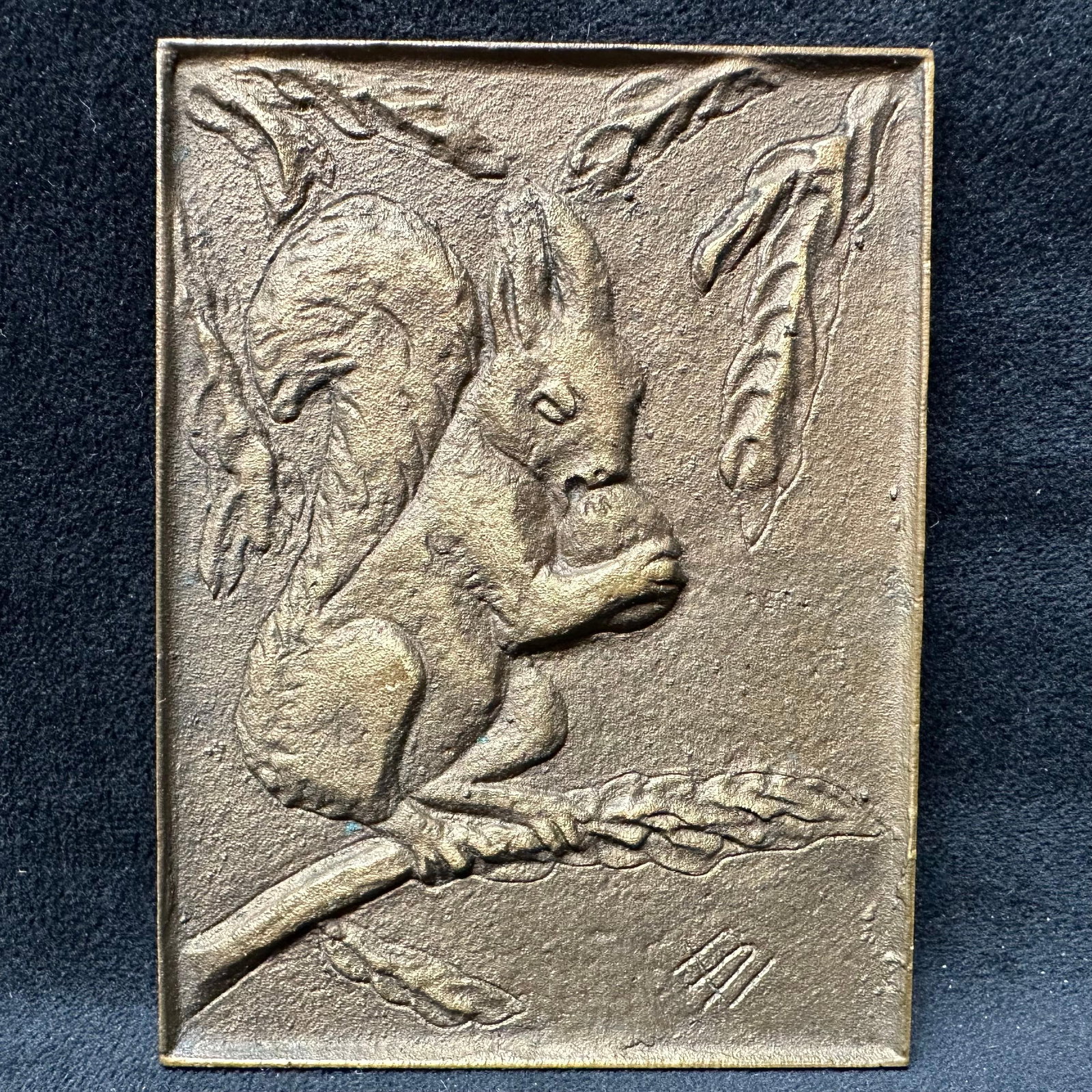 Richard Niescher Krefeld Cast Metal Squirrel Relief Plaque: Cast metal wall plaque depicting a squirrel holding a nut while perched on a branch, signed with impressed initials on the front and stamped Richard Niescher Krefeld on the reverse, rectangular f