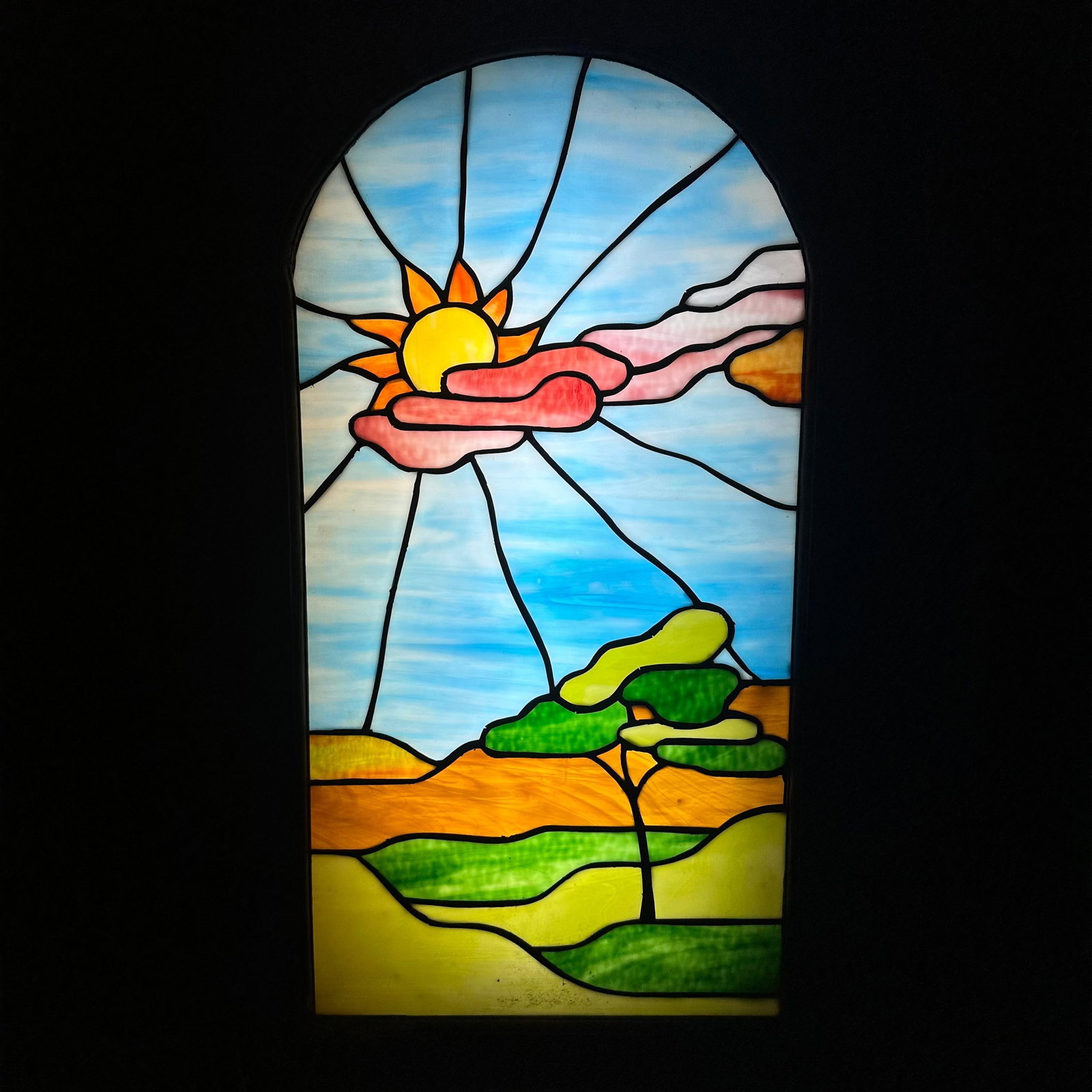 Stained Glass Light Box Panel Sun and Landscape Design Wooden Framing: A vintage stained glass light box, featuring a colorful scenic design with a rising sun over rolling hills and a tree. The glass is beautifully crafted with vivid tones of blue, green, amber, pink,