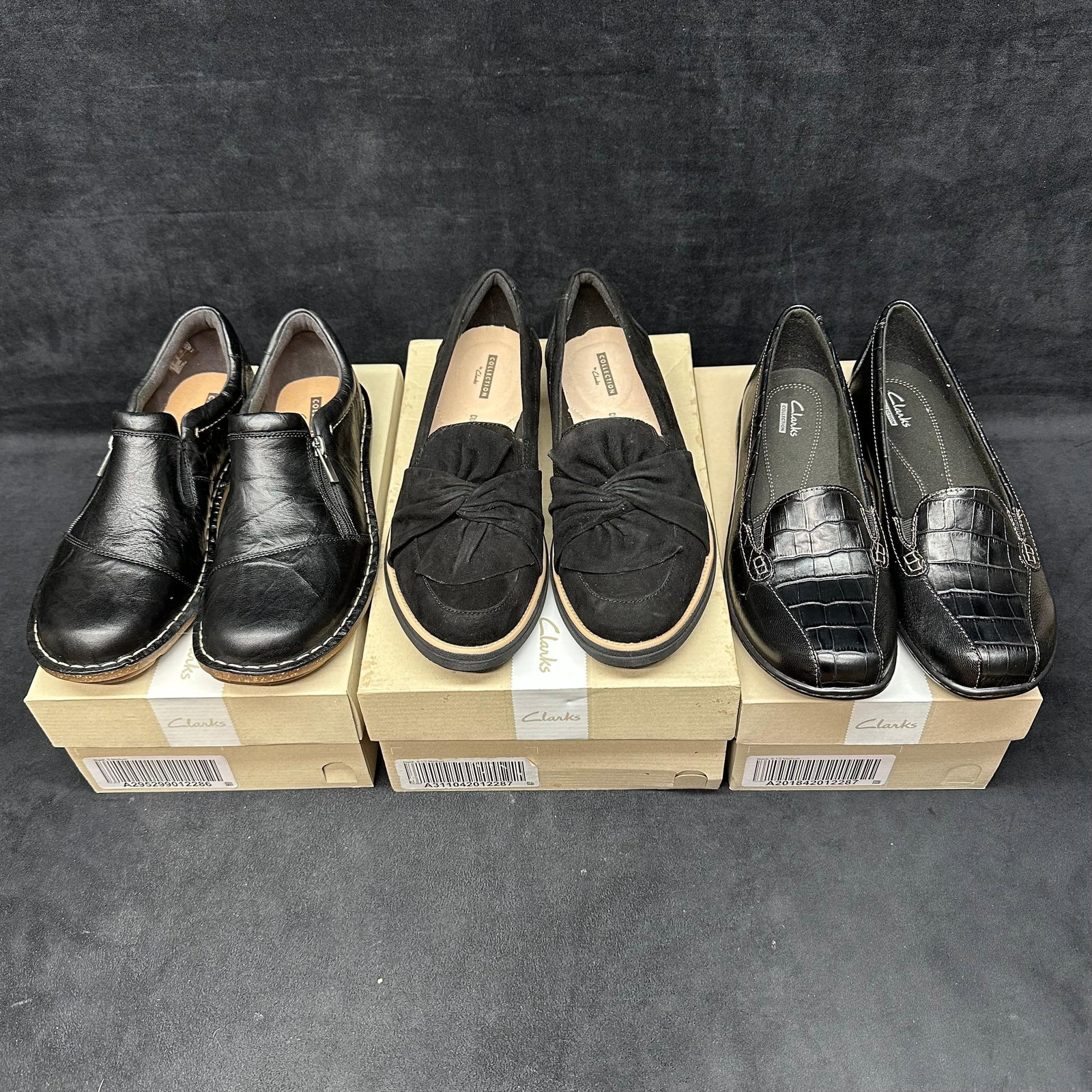 Lot of Three Pairs Clarks Women's Shoes Leather and Suede Comfort Loafers: Set of three pairs of Clarks collection women's shoes, all in black tones. Includes one pair of leather slip-ons with side zip, one pair of suede loafers with knot details, and one pair of faux cr