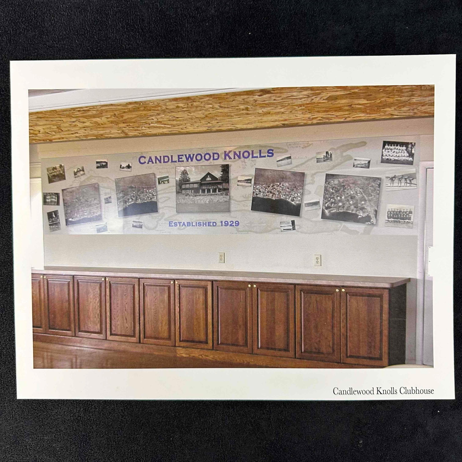 Candlewood Knolls Clubhouse Historical Wall Installation Photo Print: Photo print of a large panoramic wall installation celebrating the history of Candlewood Knolls, established in 1929. Features vintage black-and-white photographs, aerial images of the community, and 