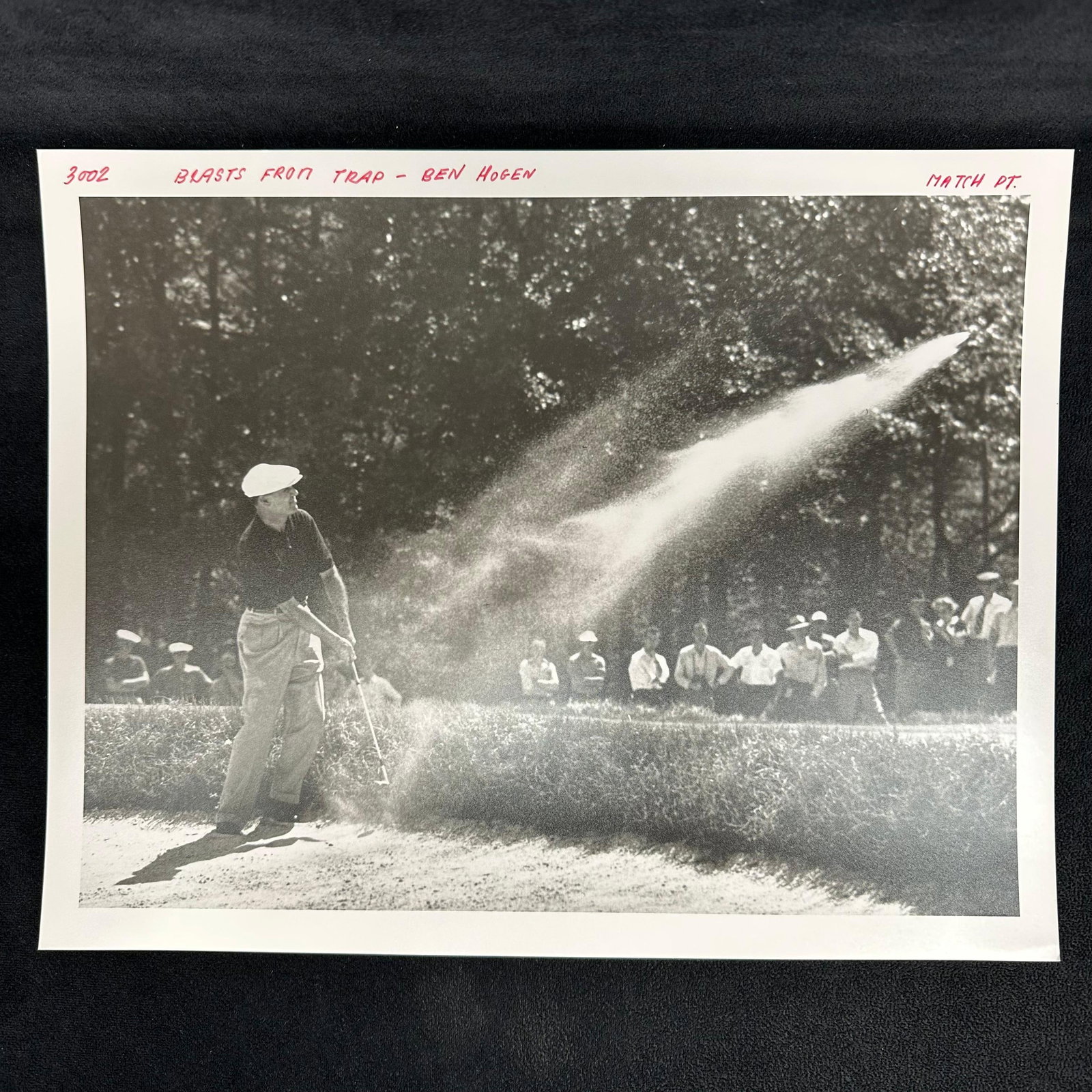 Ben Hogan Black and White Golf Golfer Action Analog Photo Print Blasts From Trap: Black and white vintage photograph capturing Ben Hogan, a professional golfer, mid-swing from a sand trap, with sand dramatically spraying across the frame. The top margin of the print features handwr
