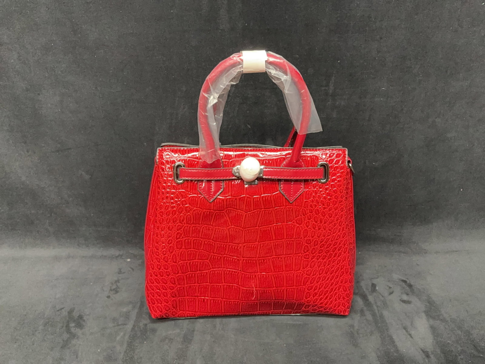 Red Croc-Print Handbag: Red croc-print leather-style handbag with structured handles and gold-tone hardware. A crack is present on one side toward the bottom as shown in the photos. Please see photos for best description of