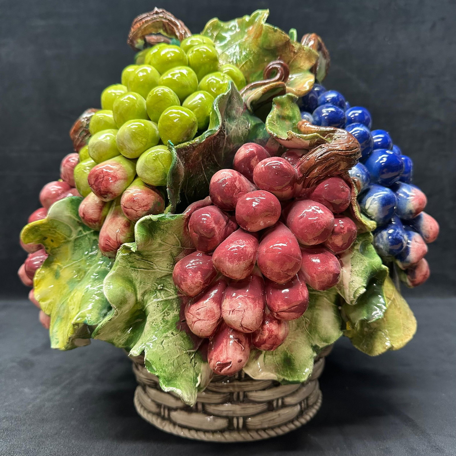 Italian Hand Painted Ceramic Grape Fruit Basket Centerpiece Italy Majolica or Capodimonte style: Large/heavy Majolica or Capodimonte style Hand-painted Italian ceramic grape basket centerpiece marked Intrade Hand Painted Made in Italy on the base. Features raised clusters of grapes in red, g