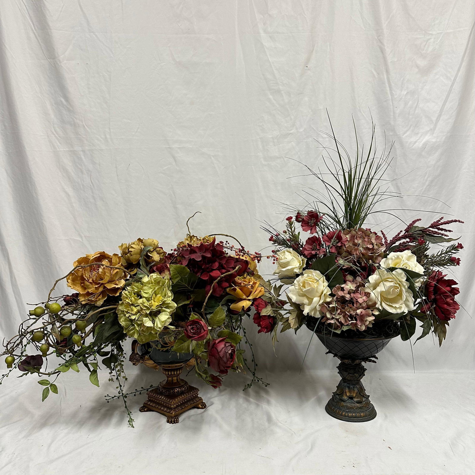 Pair of Silk Style Decorative Floral Arrangements in Ornate Urn Vase Vessels Large: Two large silk-style floral arrangements featuring mixed blooms in deep red, cream, gold, and green tones. One arrangement is housed in a highly ornate green-and-gold urn with figural handles (one is 