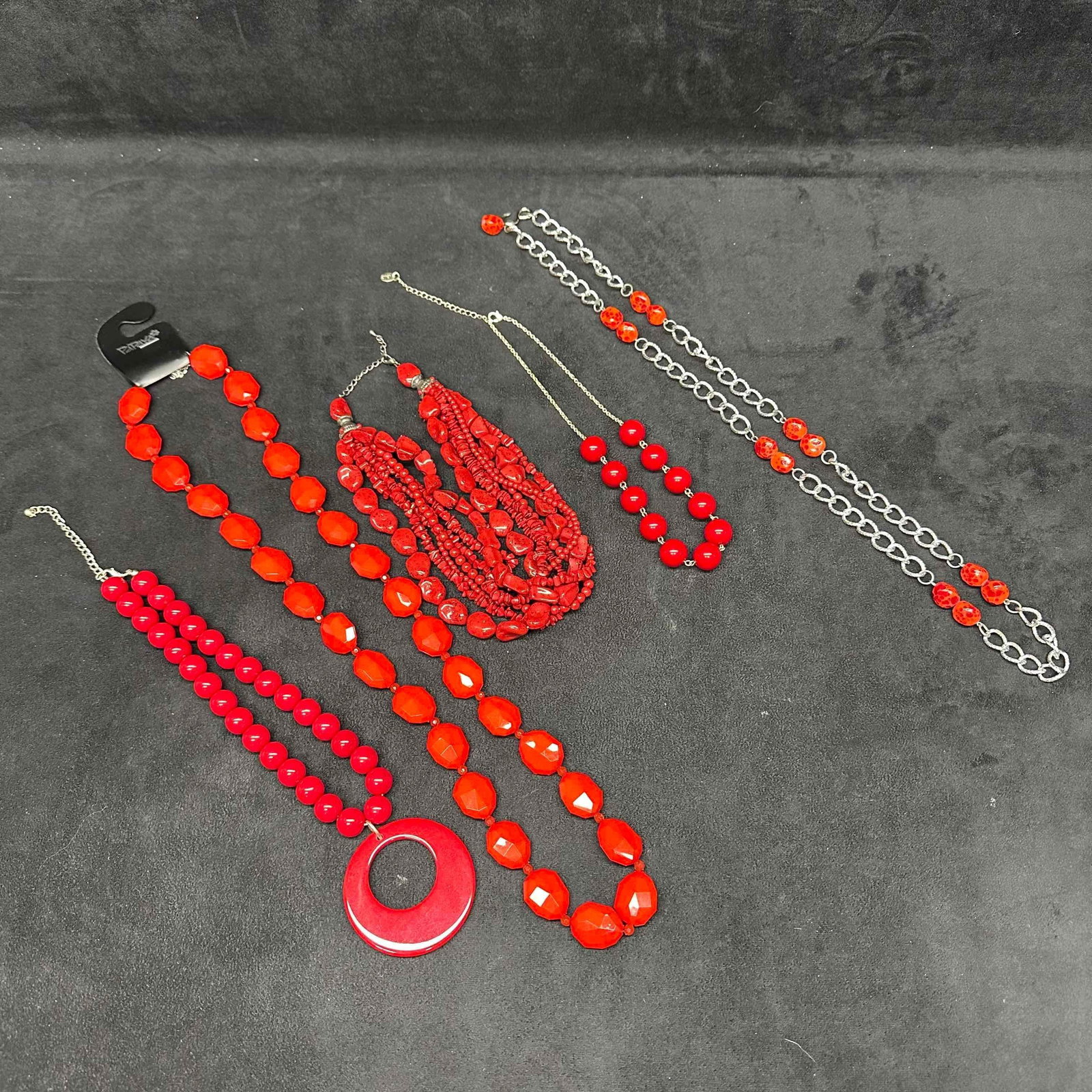 Costume Jewelry Red Plastic Faux Stone Necklace Set Lot of 5 Five Necklaces H39: Necklaces with red colored plastic beads with beautiful accent designs. Each necklace features either a j hook and lobster claw clasp closure. Some necklaces are long and have multiple strands. These 