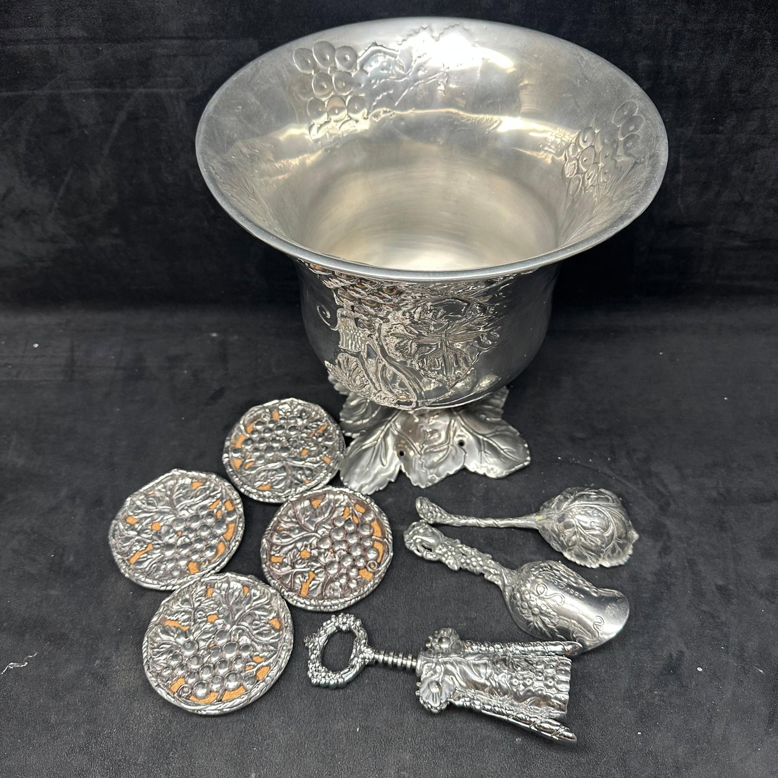 Arthur Court Grape Pattern Aluminum Serveware Group Ice Bucket Coasters Corkscrew Serving Utensils: Group of Arthur Court aluminum serving ware featuring the classic grape and vine motif. This lot includes a large footed ice bucket with leaf-form base, a set of grape-pattern round coasters, a grape 
