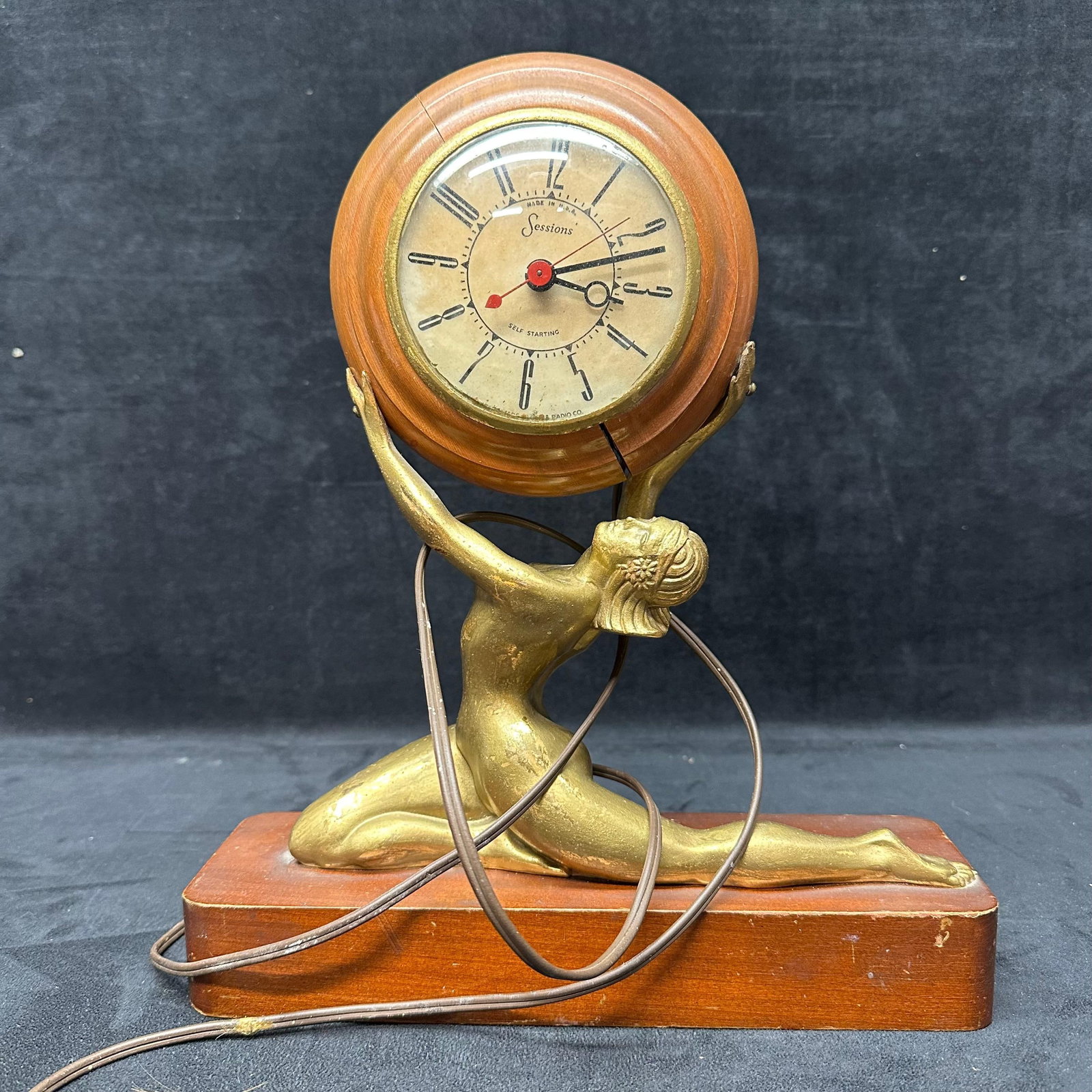 Sessions Art Deco Figural Goddess Nude Woman Mantel Clock on Wood Base: Vintage Sessions electric mantel clock featuring a gilt metal Art Deco figural nude woman form supporting a round wooden clock housing, mounted on a rectangular wooden base. Marked Sessions on th